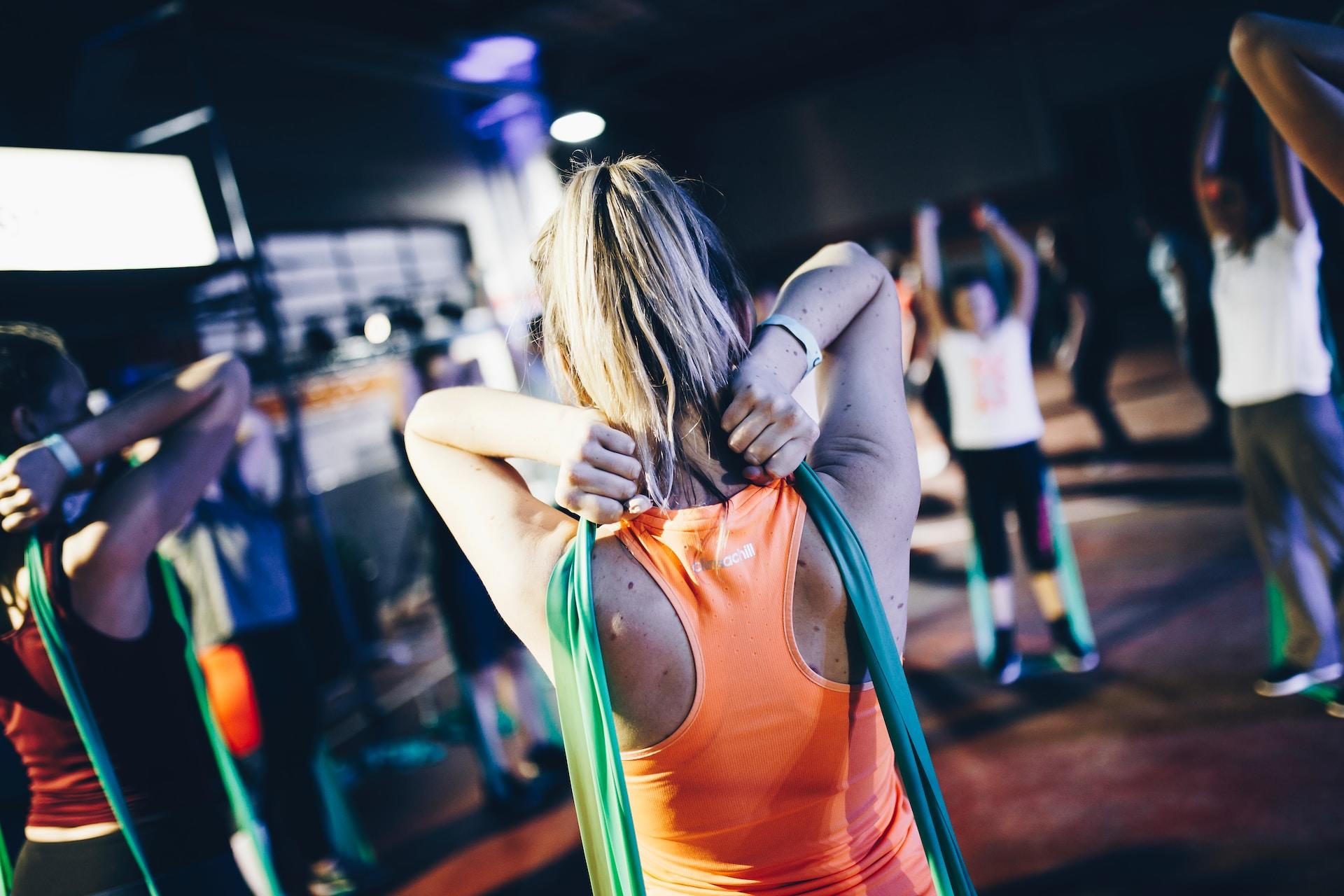 Frau in Sportsachen mit elastischem Band an Schulter.