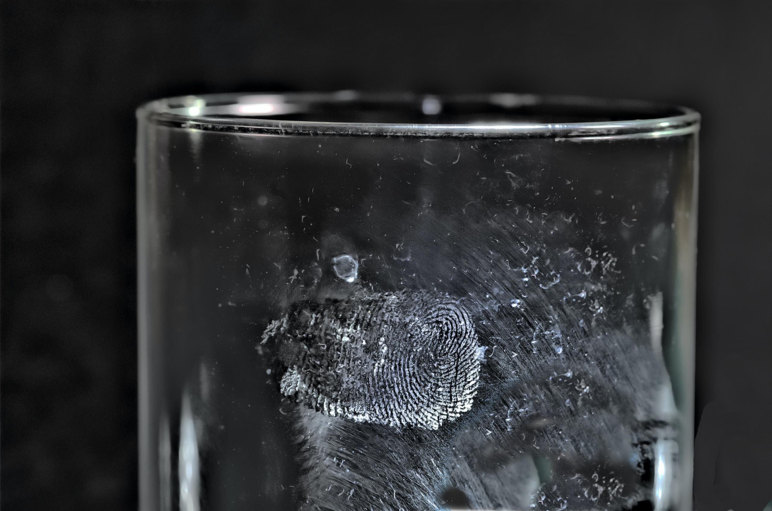 Auf einem transparenten Glas ist ein Fingerabdruck in weißem Pulver.