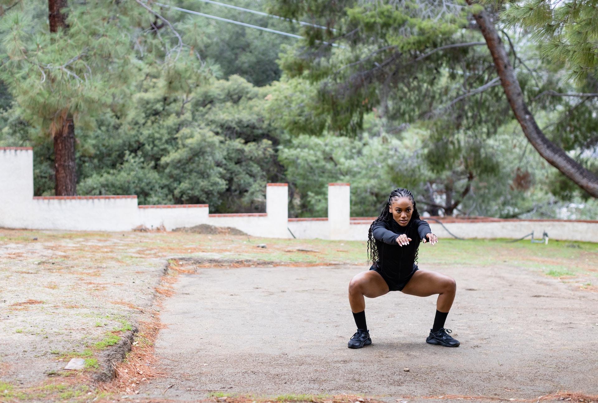 Eine Frau macht in der Natur eine Kniebeuge.