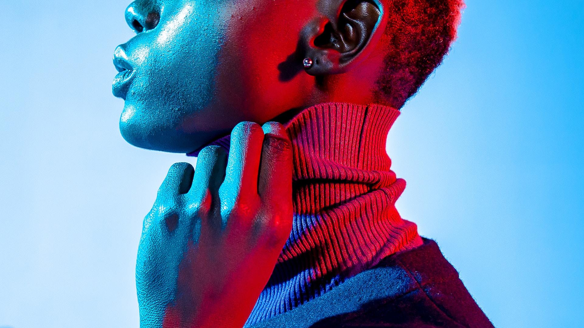 Eine Person trägt ein Kleidungsstück mit Rollkragen und legt ihre Hand an den Hals.