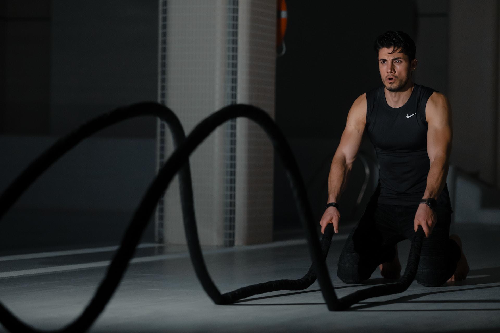 Mann kniet und hält zwei Seile in den Händen.