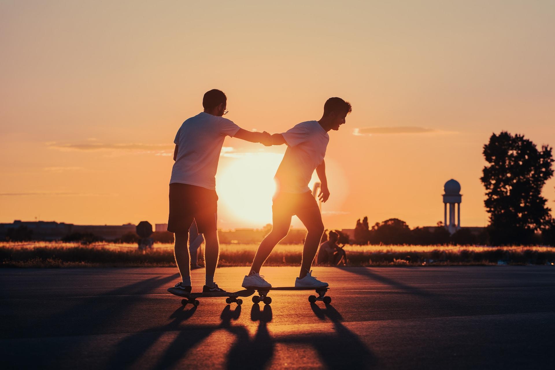 Zwei Skater auf ihren Boards bei Sonnenuntergang.