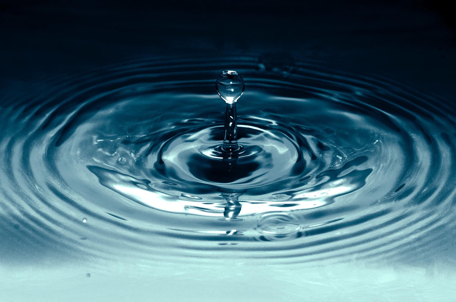 Wasseroberfläche mit einfallendem Tropfen.