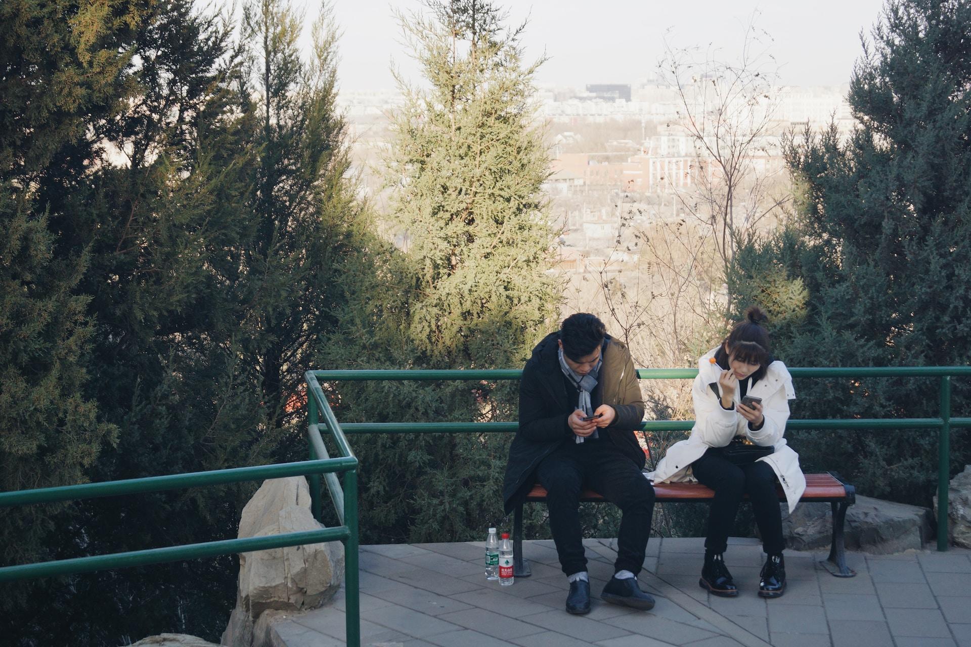 Zwei Menschen sitzen auf Bank in einem Park.