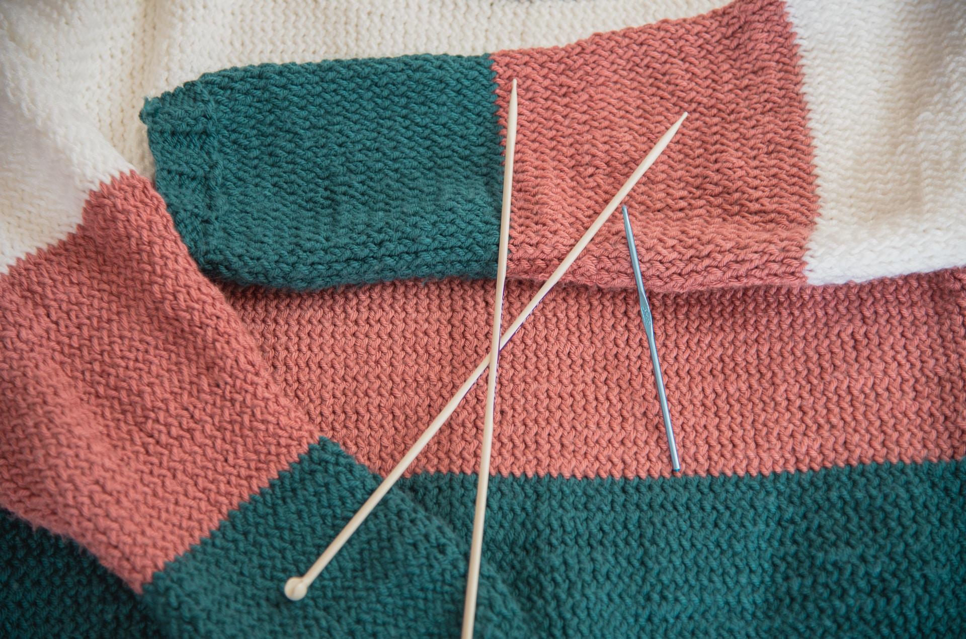 Rot und grüner Pulli mit Stricknadeln oben drauf.