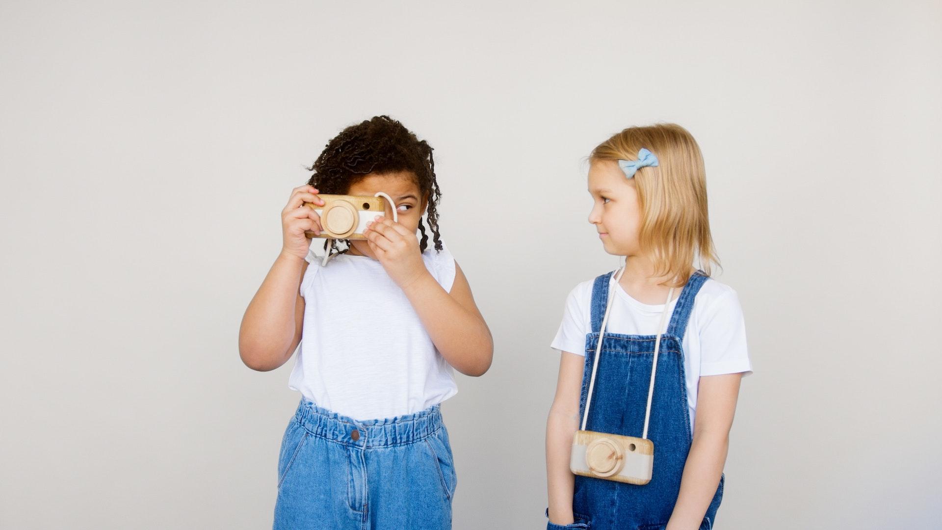 Zwei Kinder mit Fotokameras aus Holz