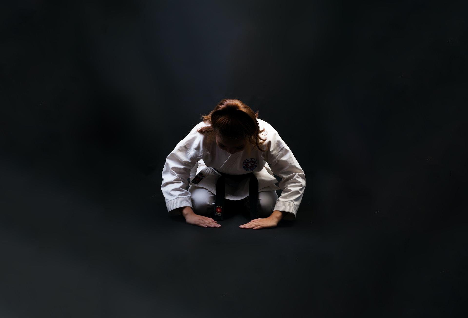 Frau in Judoanzug auf schwarzem Boden.