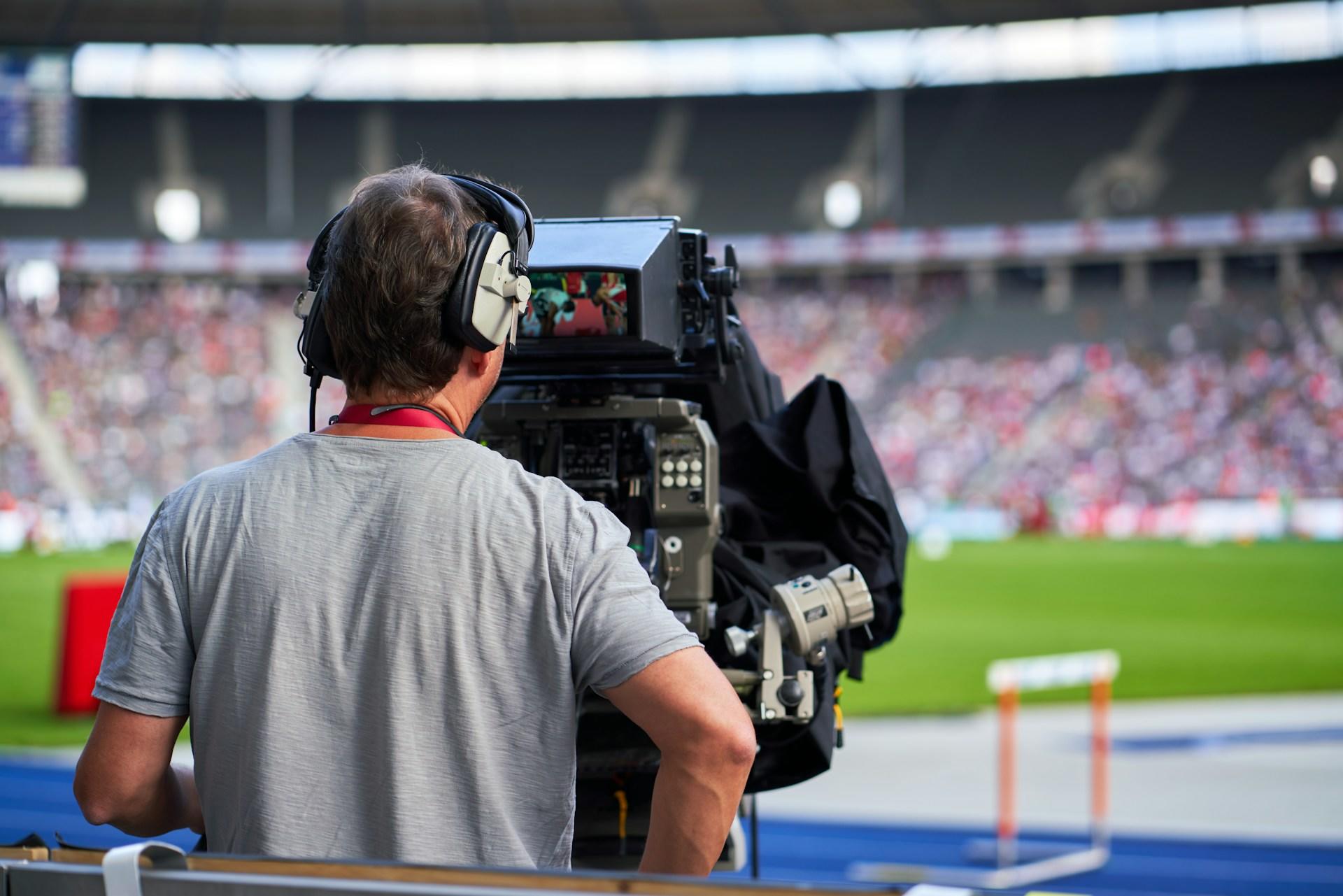Eine Person filmt mit einer großen Kamera ein Fußballstadion