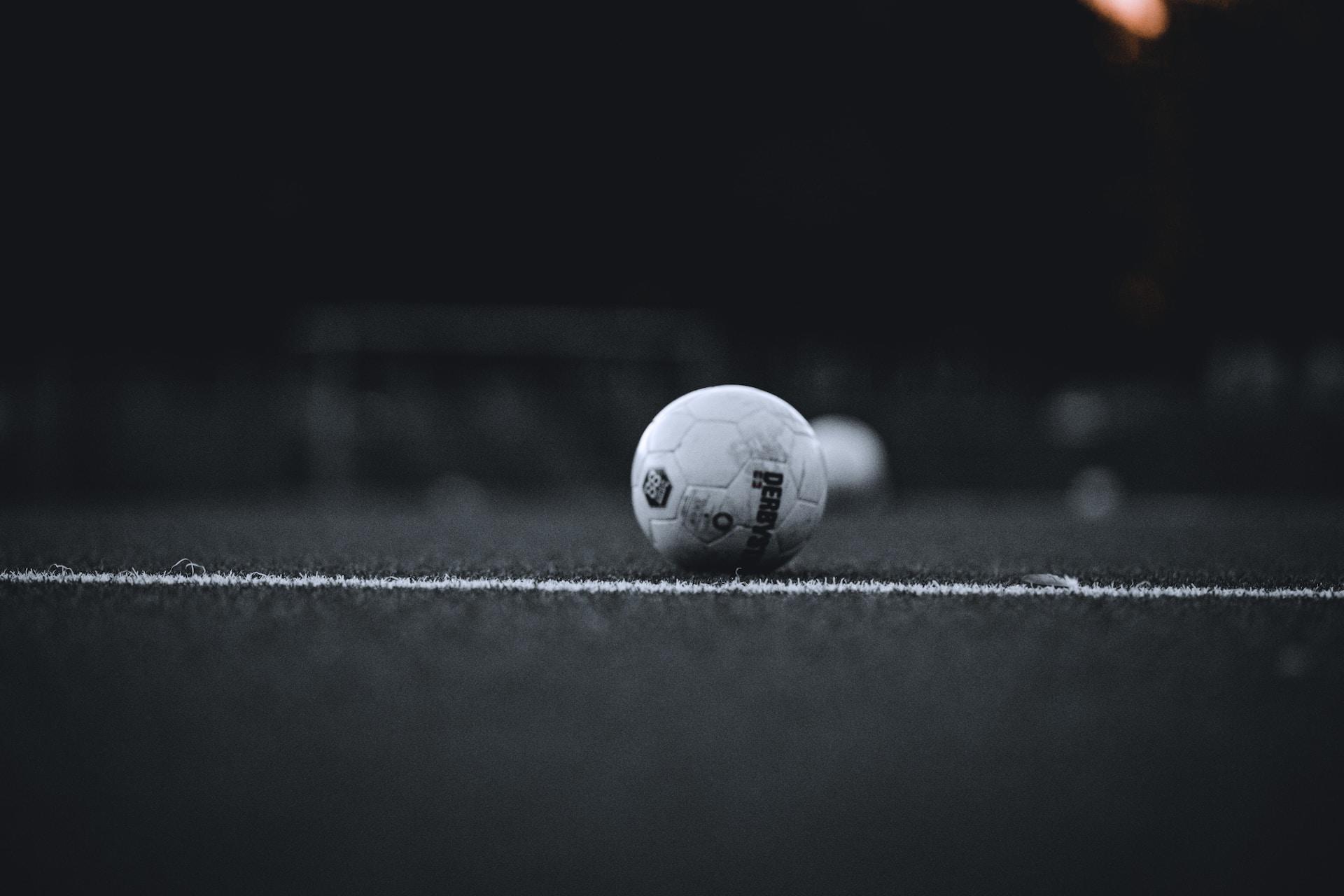ein Fußball liegt hinter einer weißen Linie