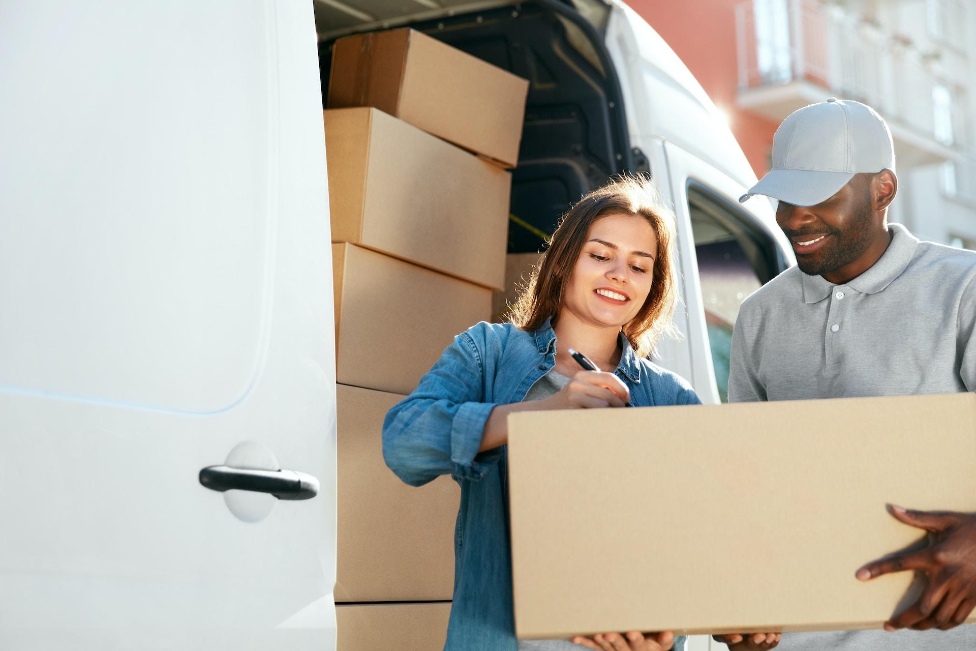 zwei Personen und ein großes Paket vor einem Auto