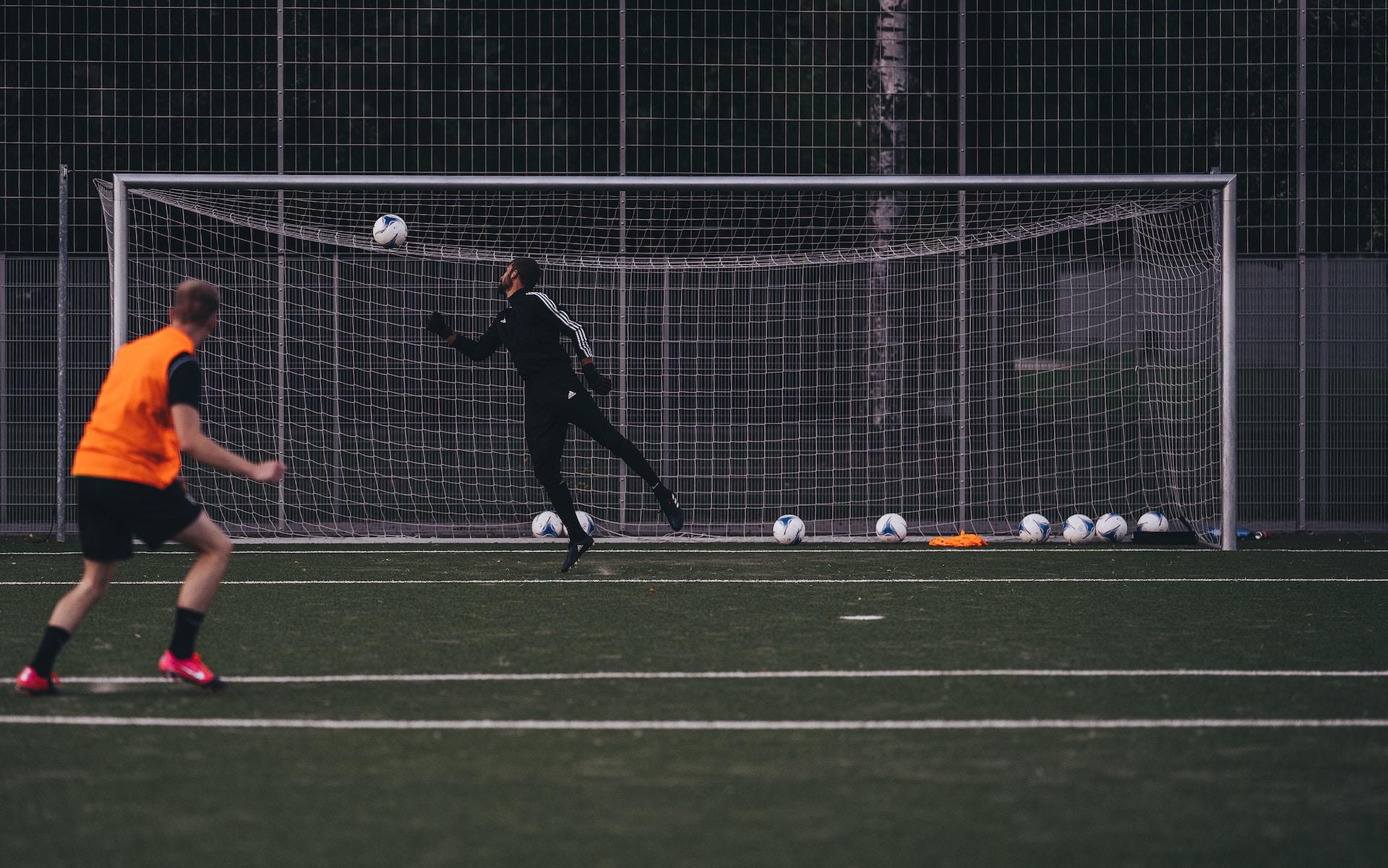 Ein Fußball fliegt ins Tor und zwei Spieler schauen ihm hinterher