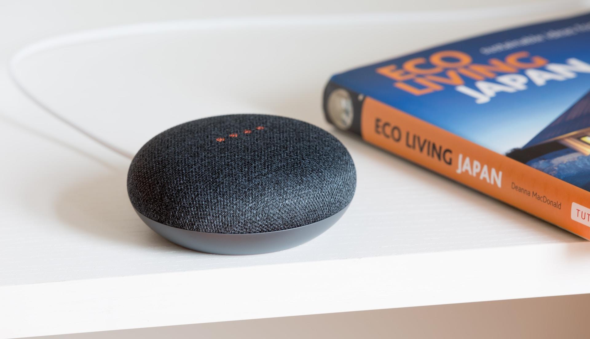 Smart Assistant auf einer Ablage neben einem Buch.