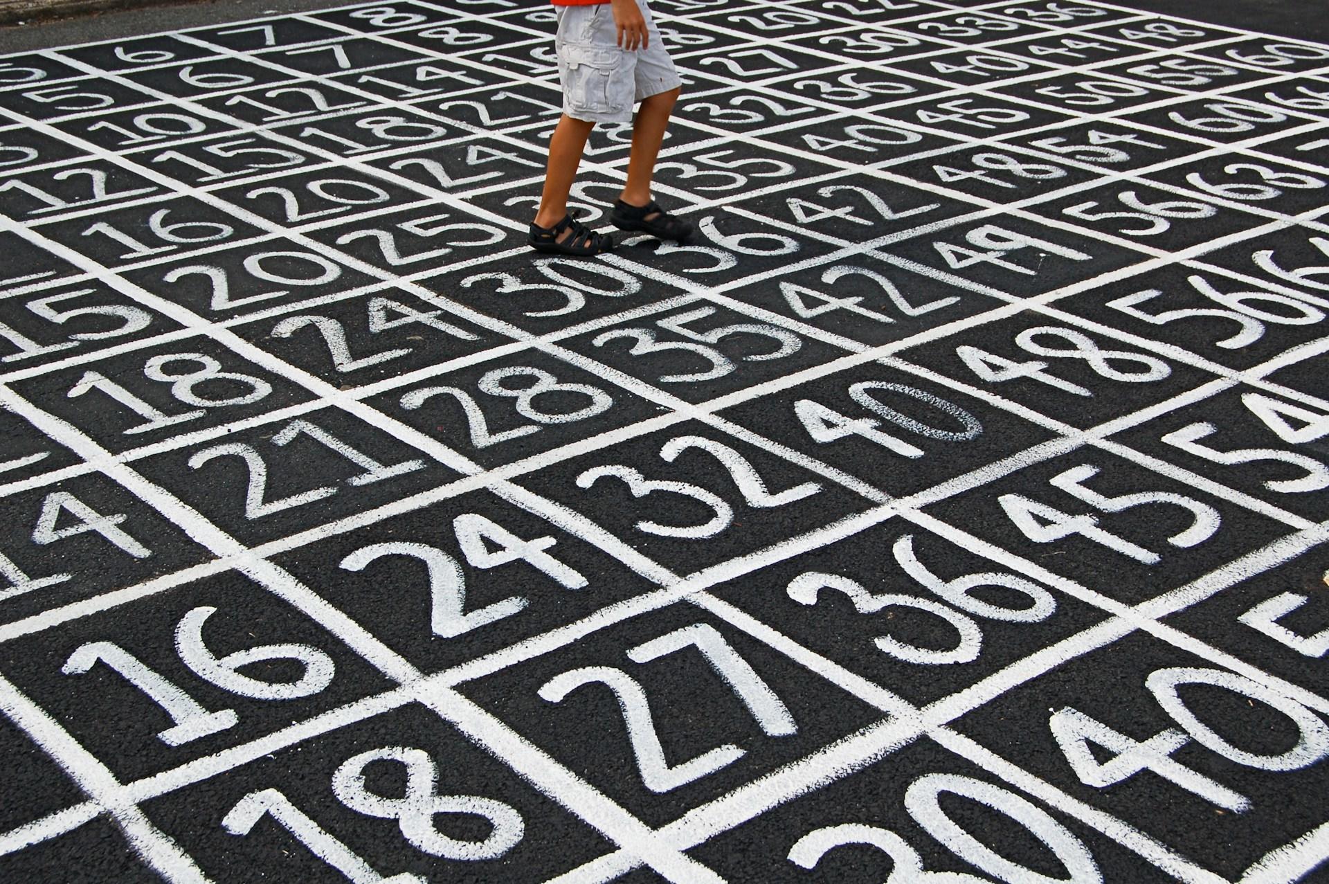 Asphalt mit weißen Zahlenfeldern und Person drauf.