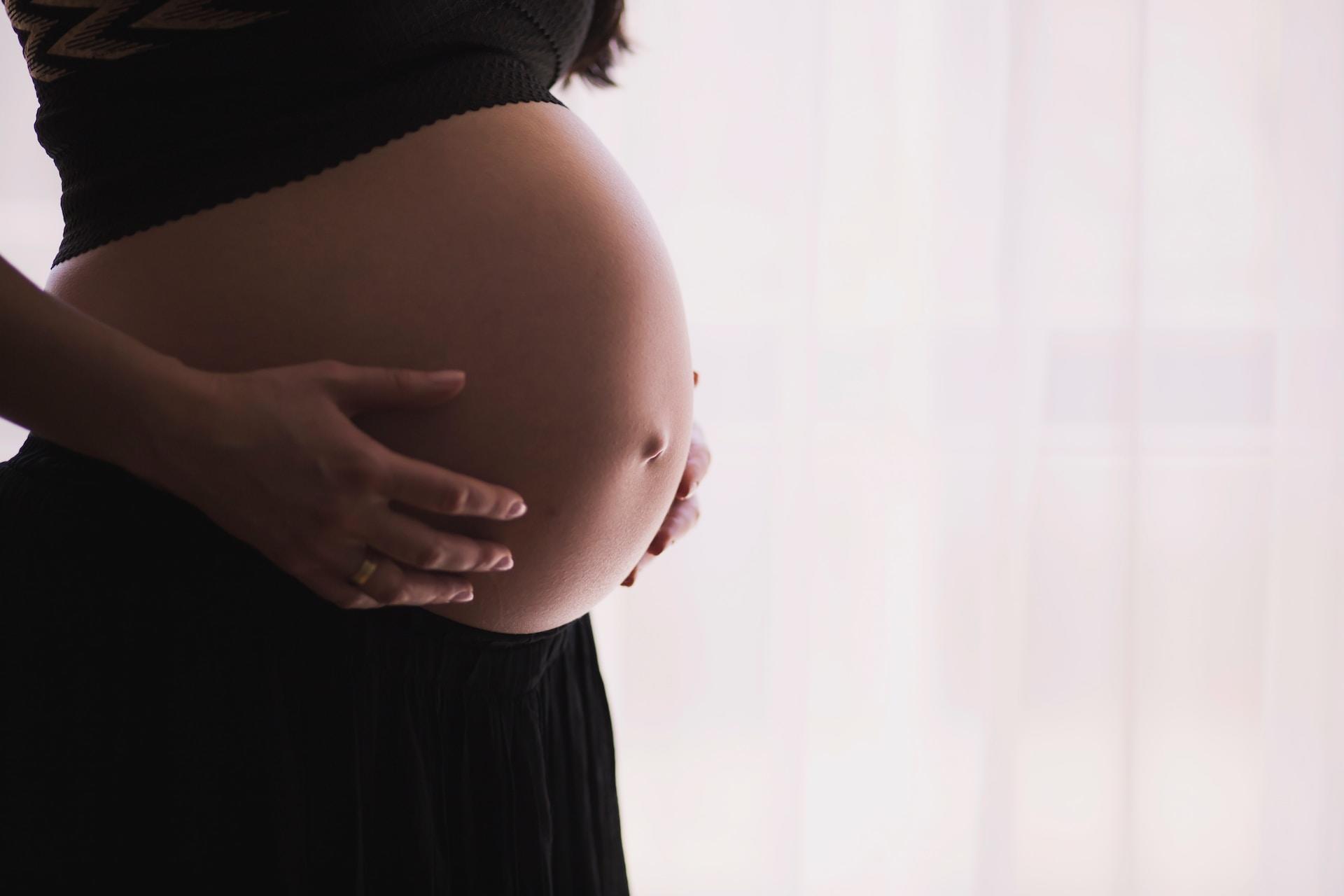 Eine Person hält ihre Hände an den Schwangerschaftsbauch
