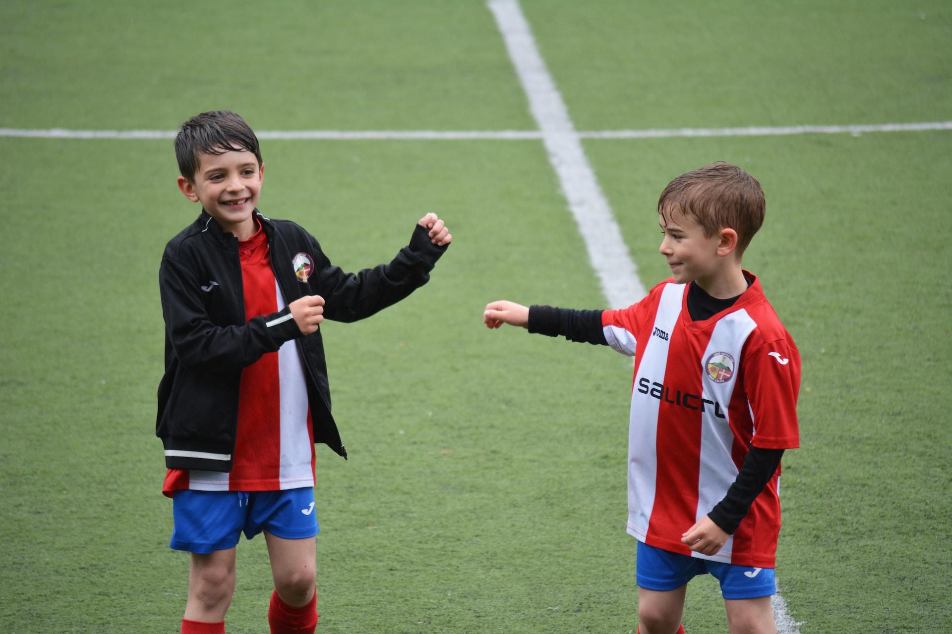 Zwei Jungs in Trikots auf einem Fußballplatz.
