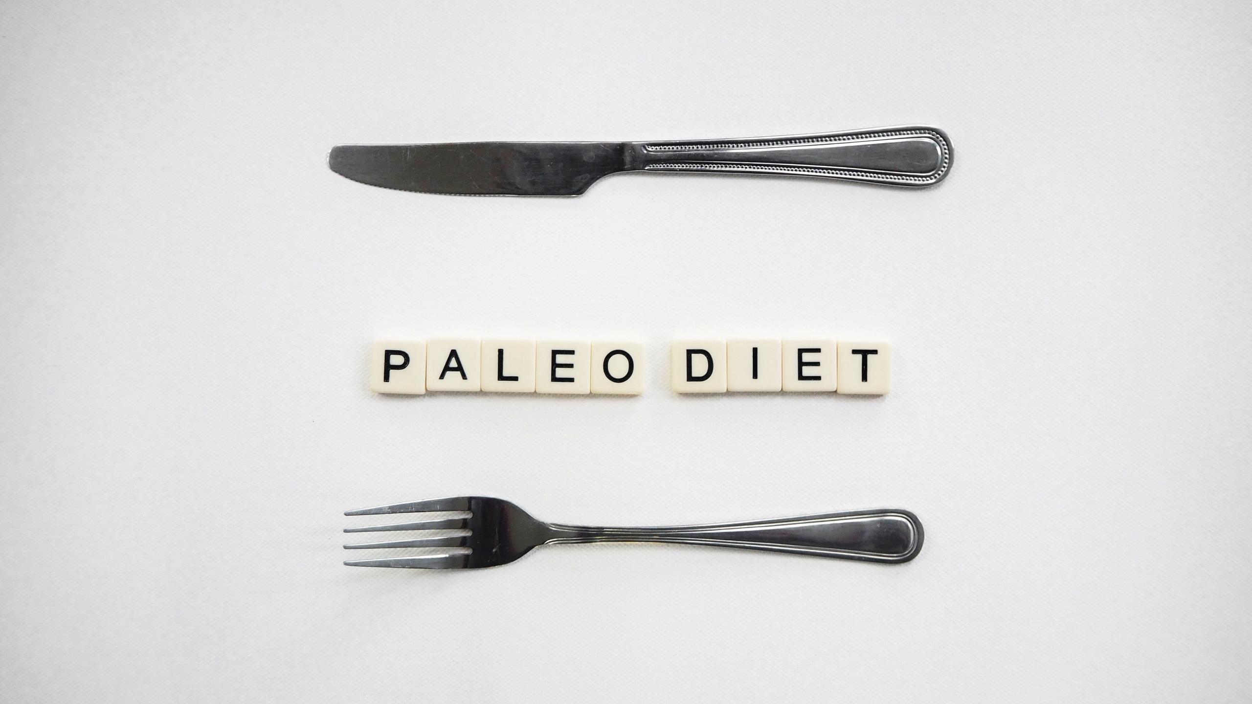 Messer und Gabel, dazwischen das Wort "Paleo Diät" mit Steinchen gelegt.