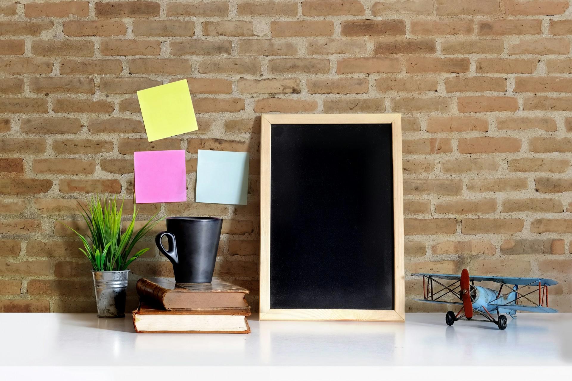 eine Tafel und ein eine Tasse und Bücher und Post Its an einer Wand