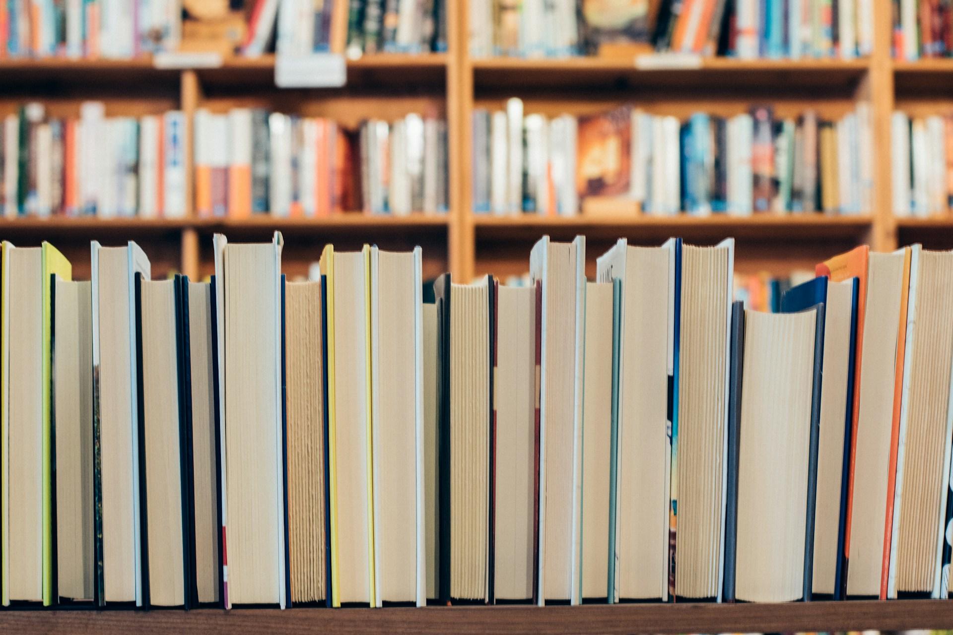 Mehrere Bücher nebeneinander vor Regal.