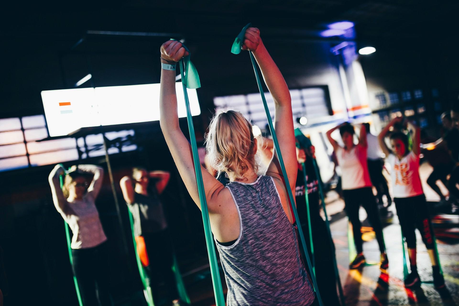 Kurs im Fitnessstudio mit mehreren Menschen in Sportsachen.