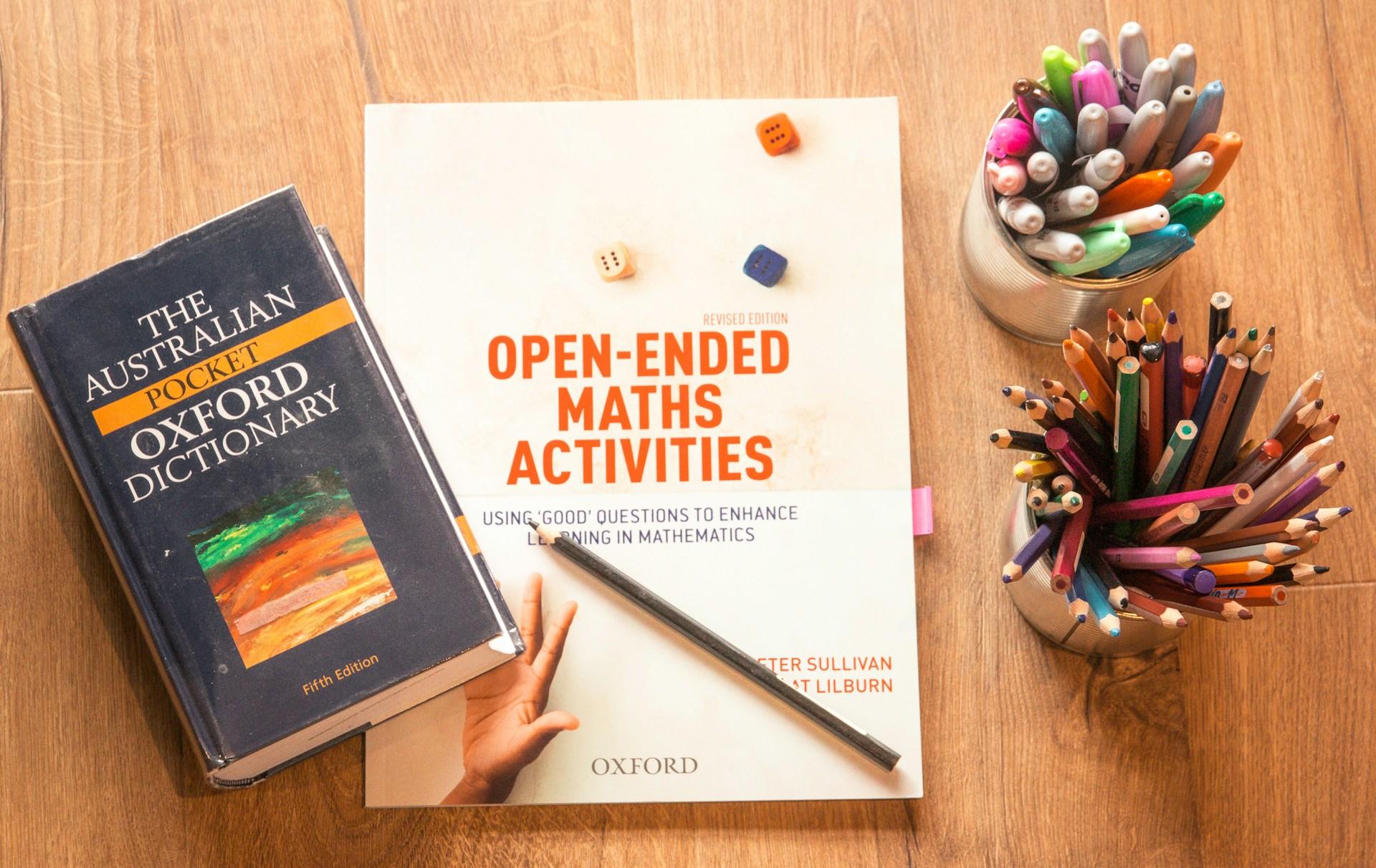 Zwei Bücher auf einem Tisch neben Stiften.