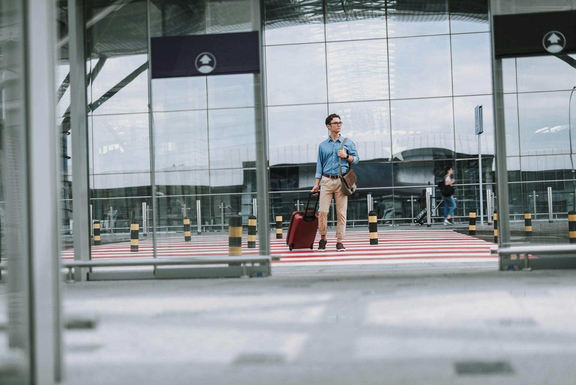 eine Person mit Rollkoffer an einem Flughafen