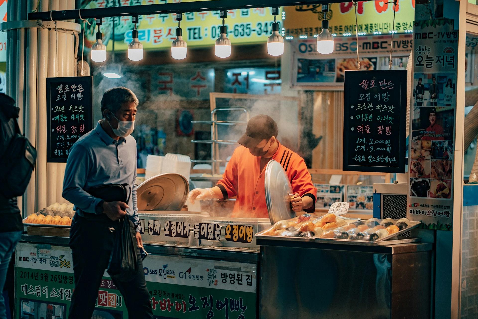 Imbissstand in Korea mit Mann an der Theke.
