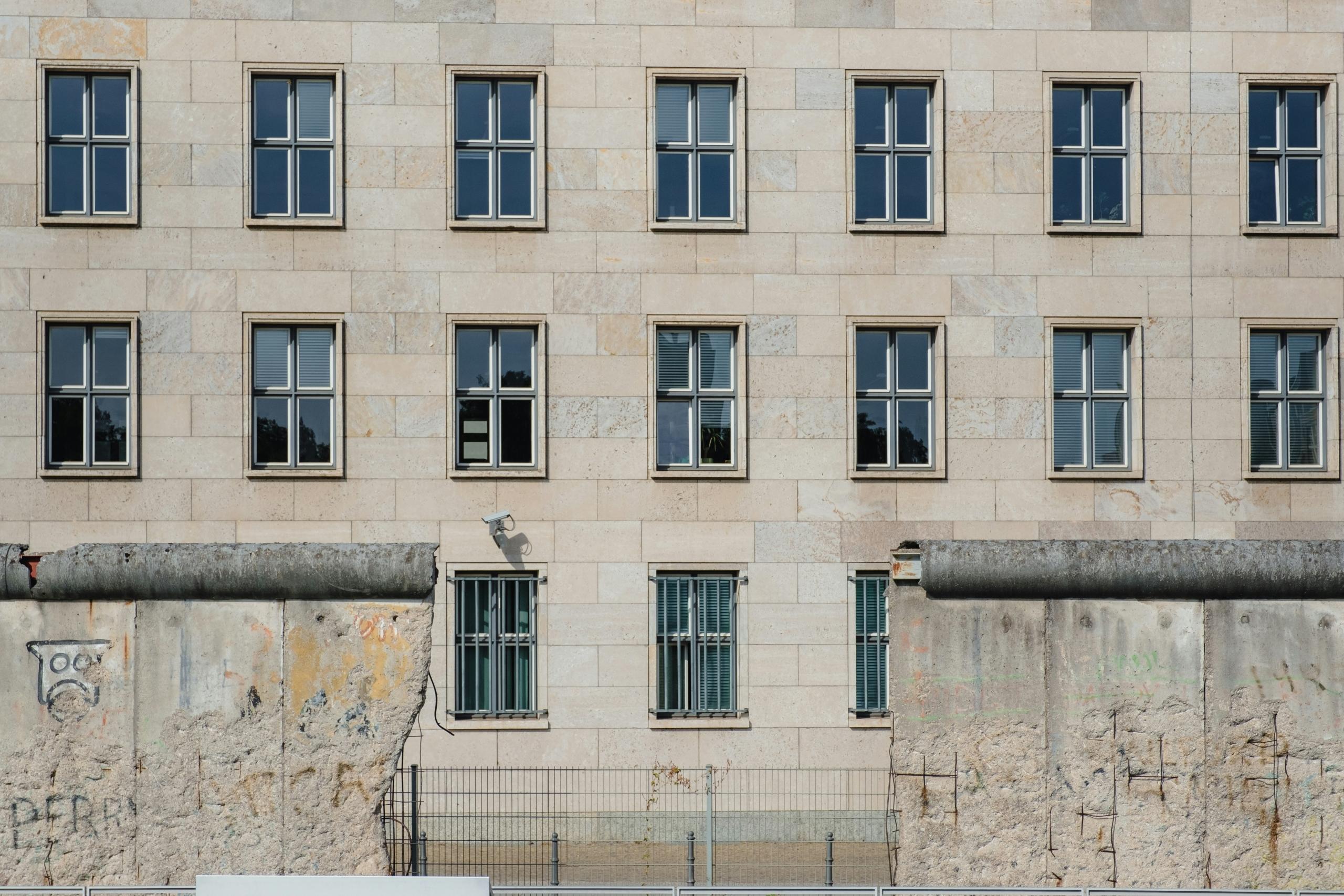 Man kann durch eine Lücke in der Berliner Mauer auf ein gebäude schauen.