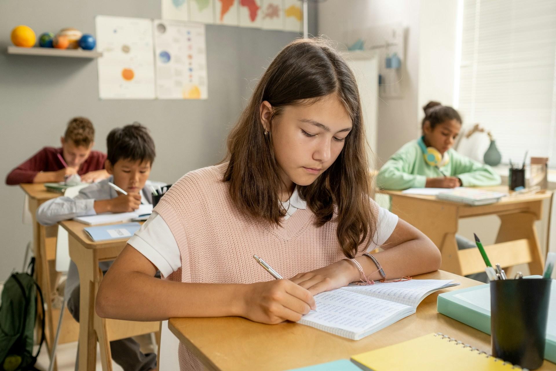Mehrere Schüler sitzen in einem Klassenzimmer und schreiben in Heft