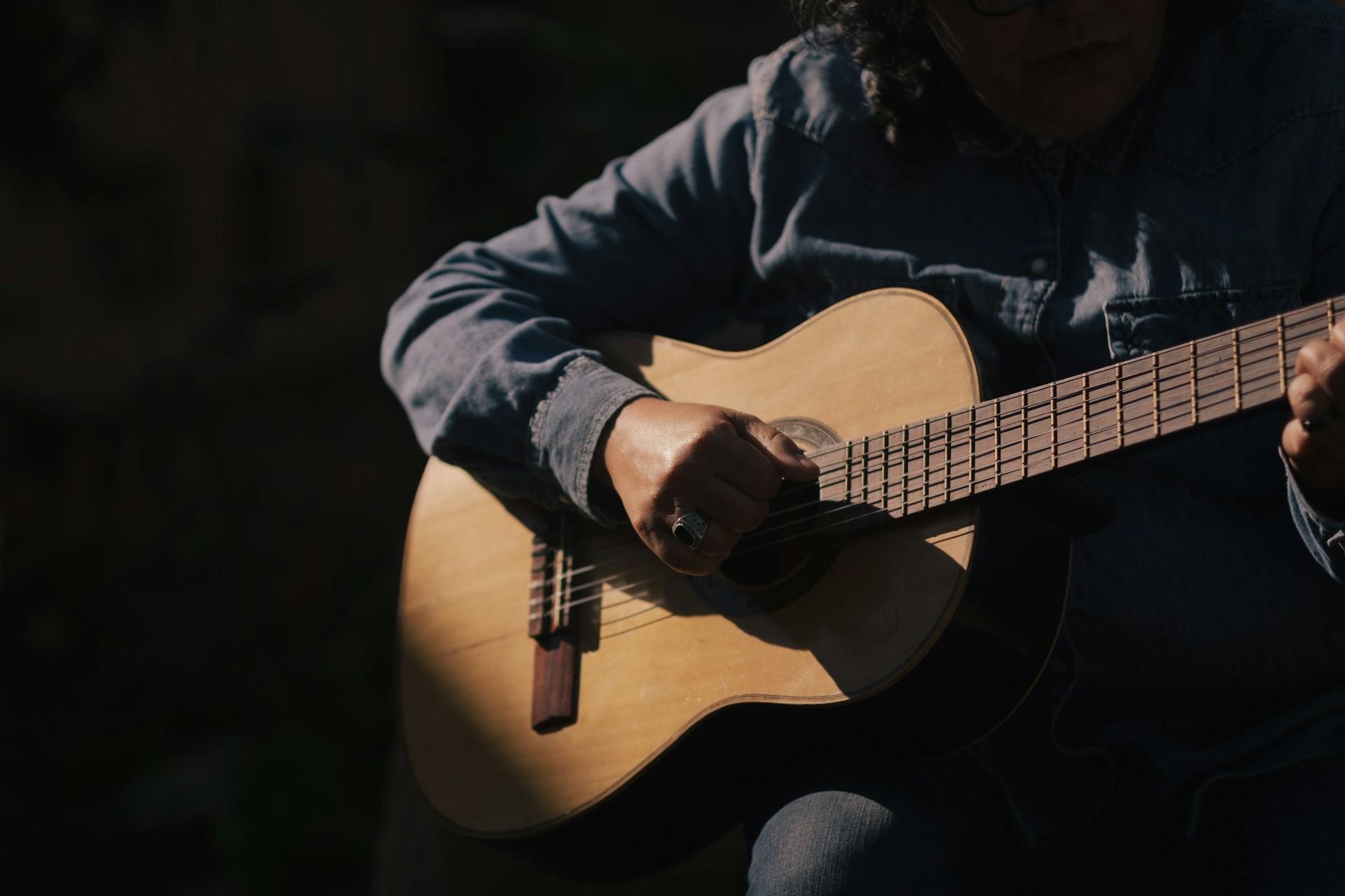 Das Gesicht einer Gitarre spielenden Person ist nicht zu sehen