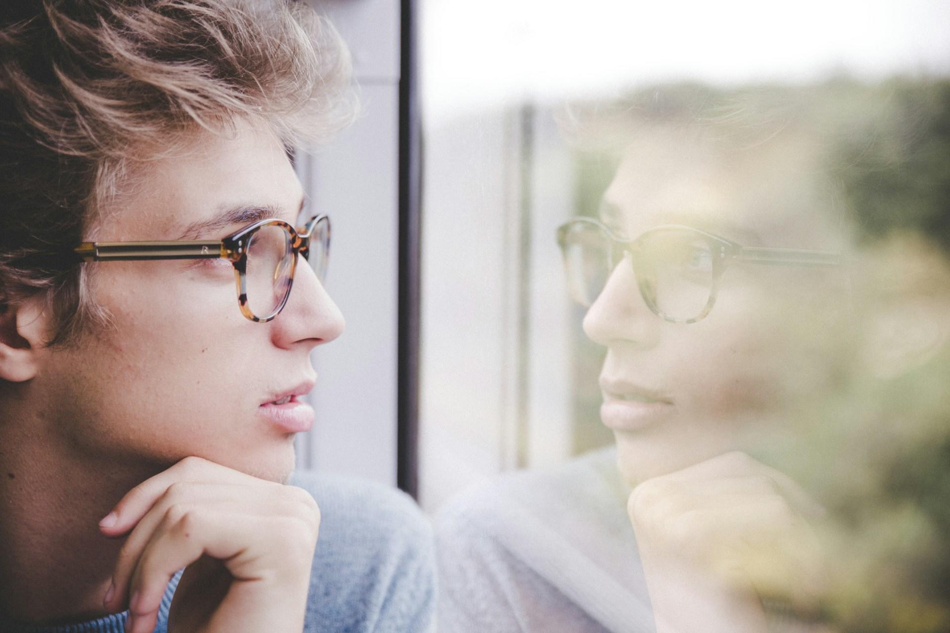 Mann mit Brille schaut aus einem Fenster