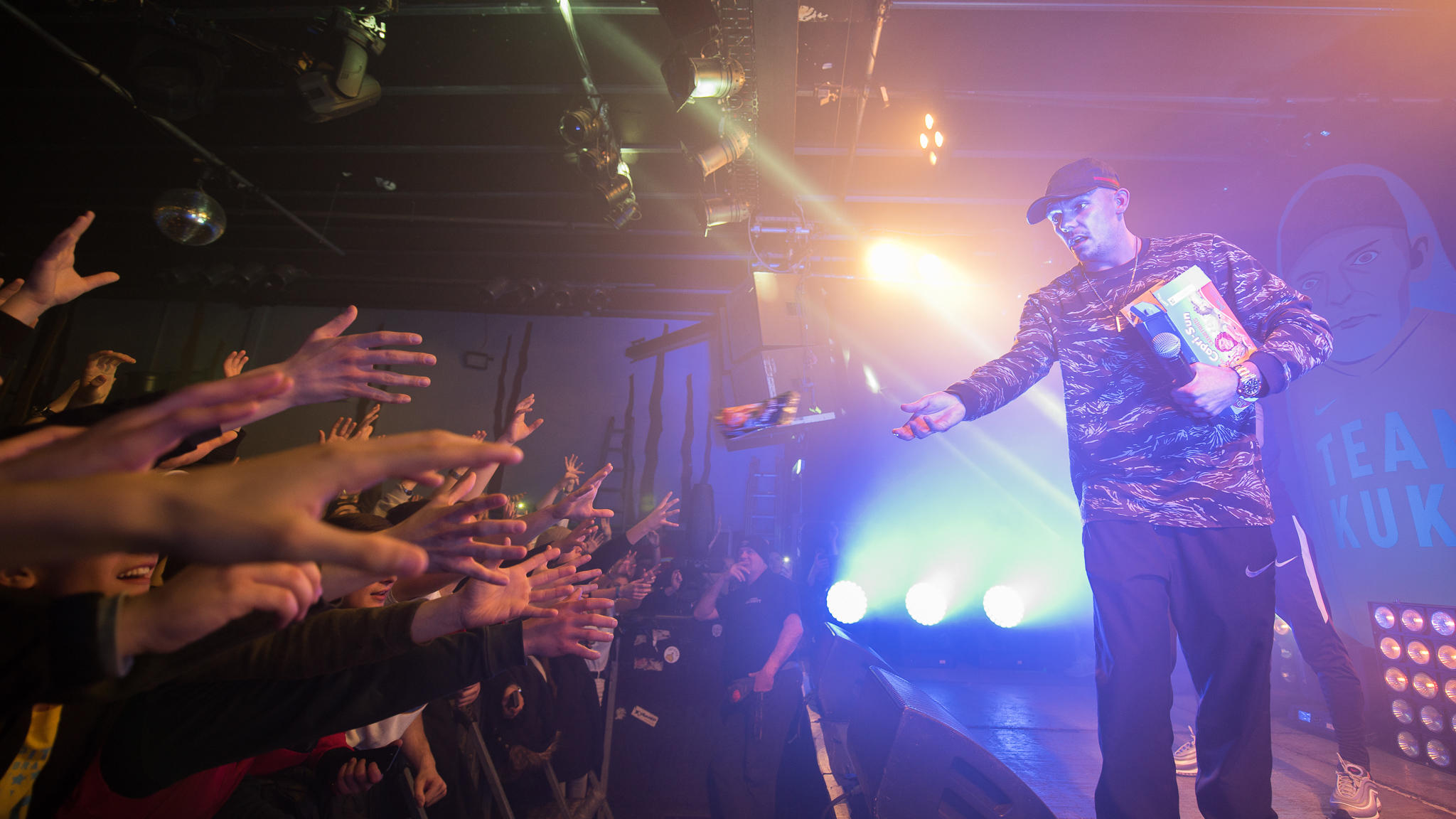 Der Rapper Capital Bra steht auf der Bühne und wirft ein Erfrischungsgetränk in die Menge.
