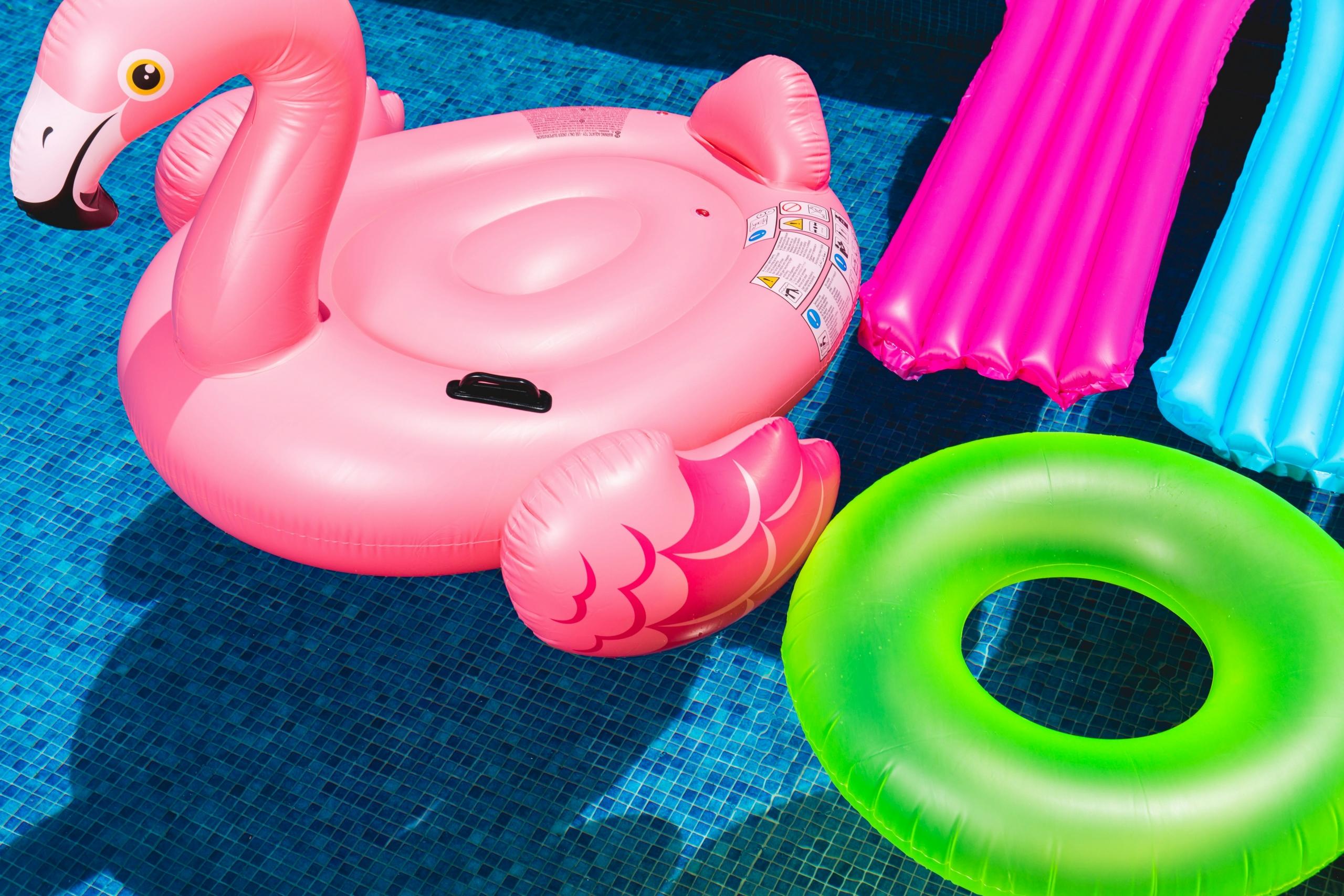 Schwimmreifen, ein aufblasbarer Flamingo und Luftmatratzen im Pool