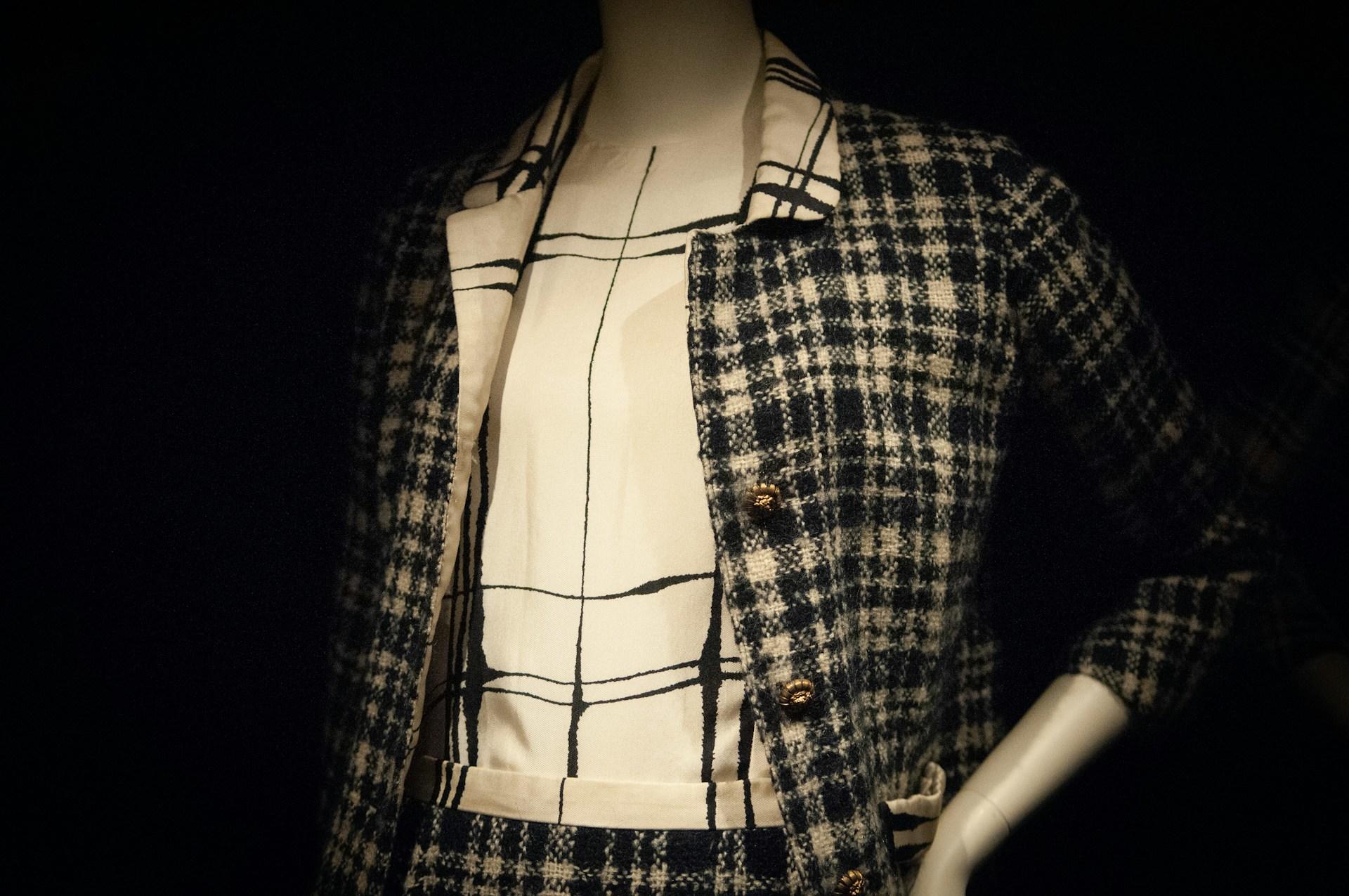 Eine weiße Bluse und eine karierte Jacke an einer Puppe