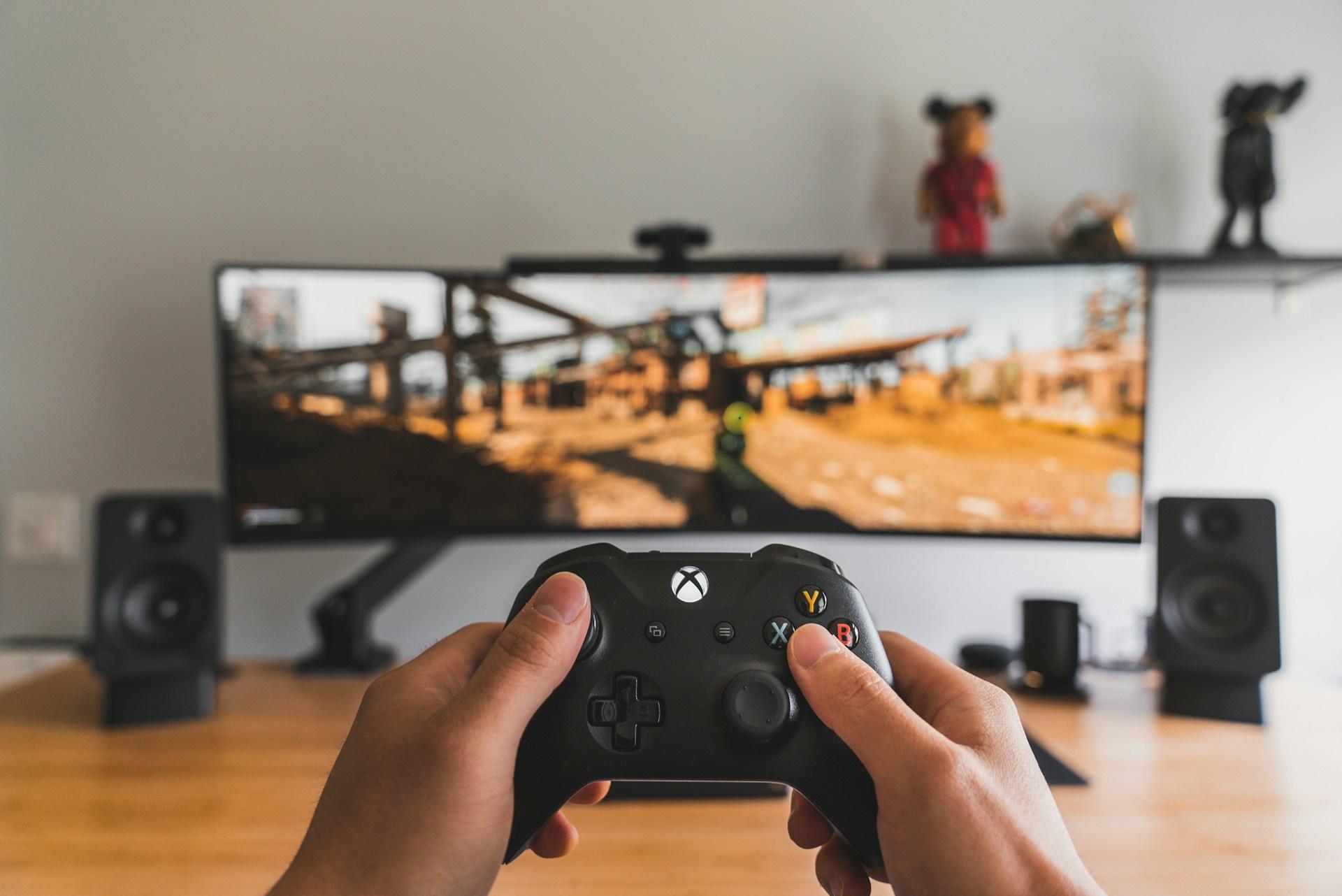 Person hält Controller vor Bildschirm.