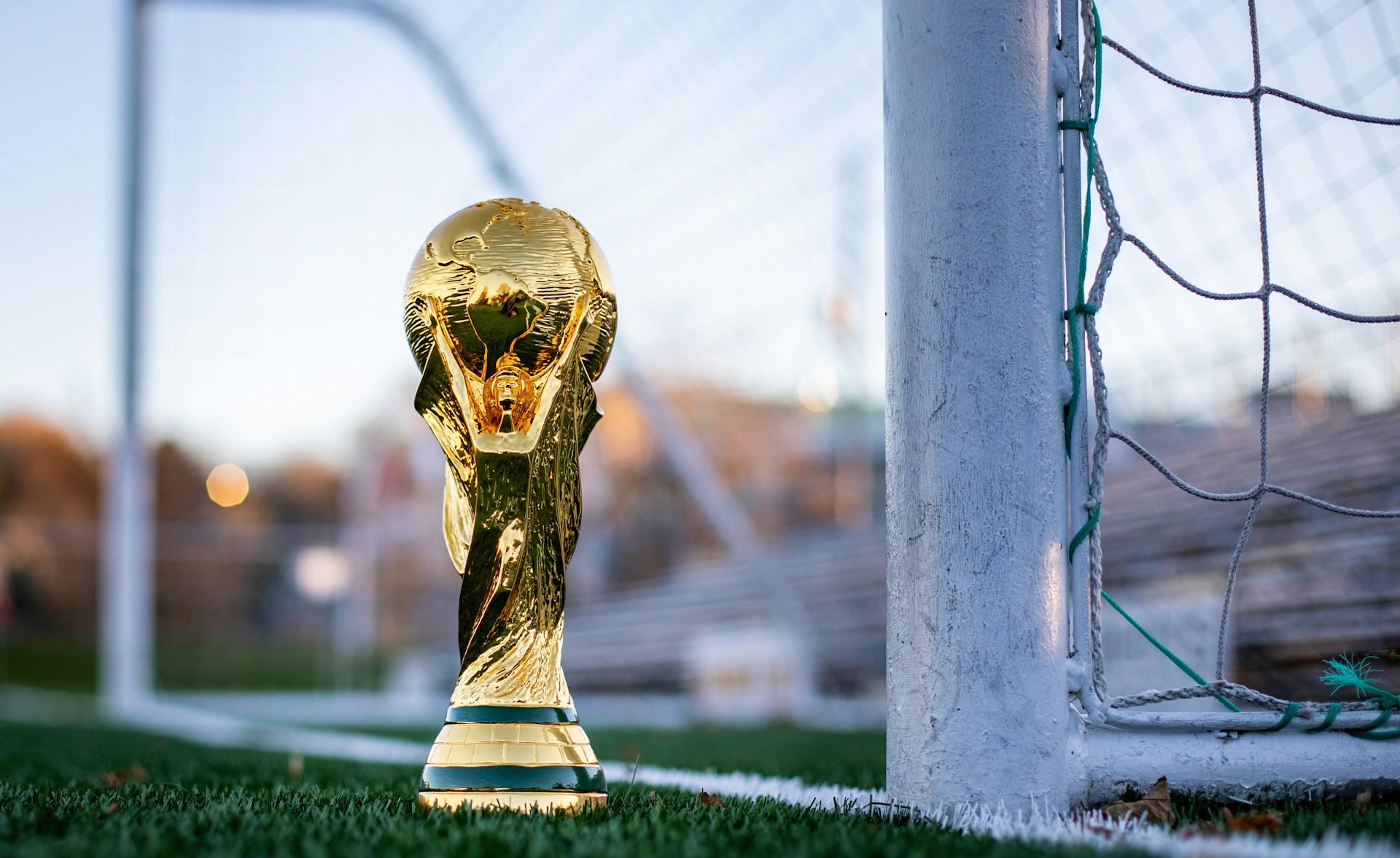 Goldener Pokal steht auf Linie zwischen einem Tor.