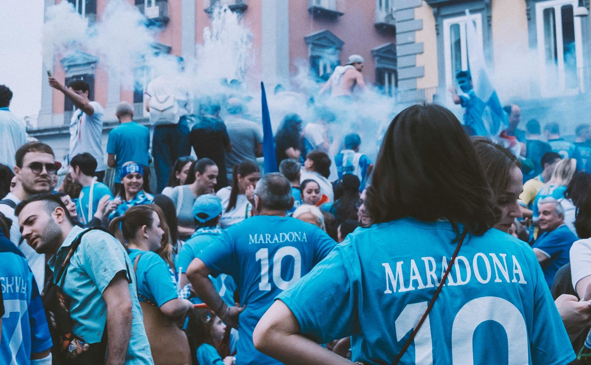 Fußballfans in blauen Trikots auf der Straße.