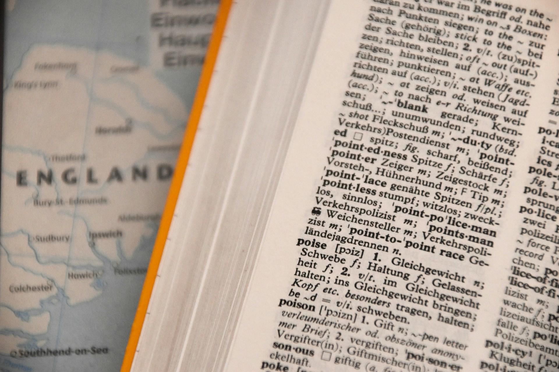 Aufgeschlagenes Wörterbuch auf Landkarte.