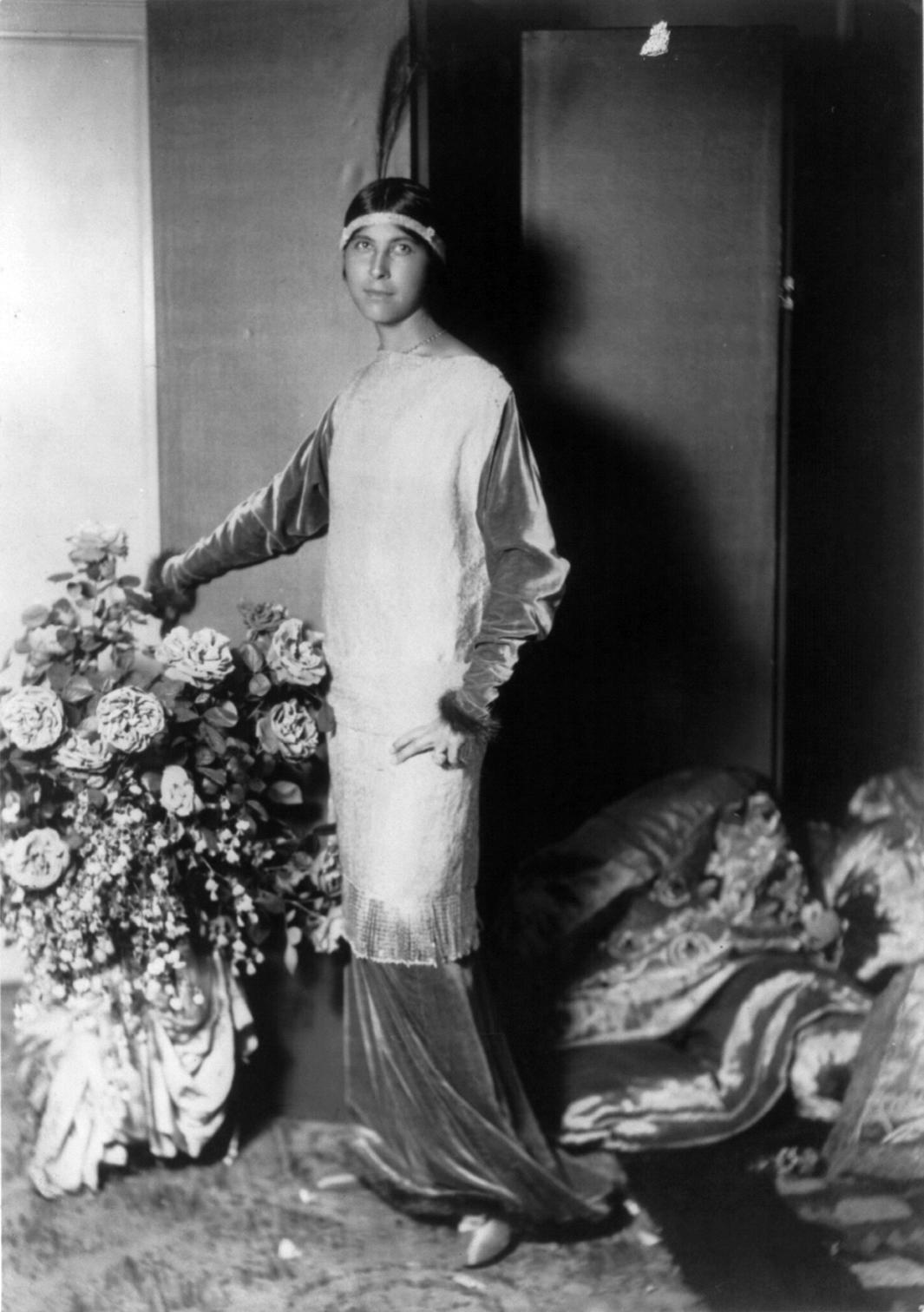 Person in langem Kleid und mit Feder auf dem Kopf