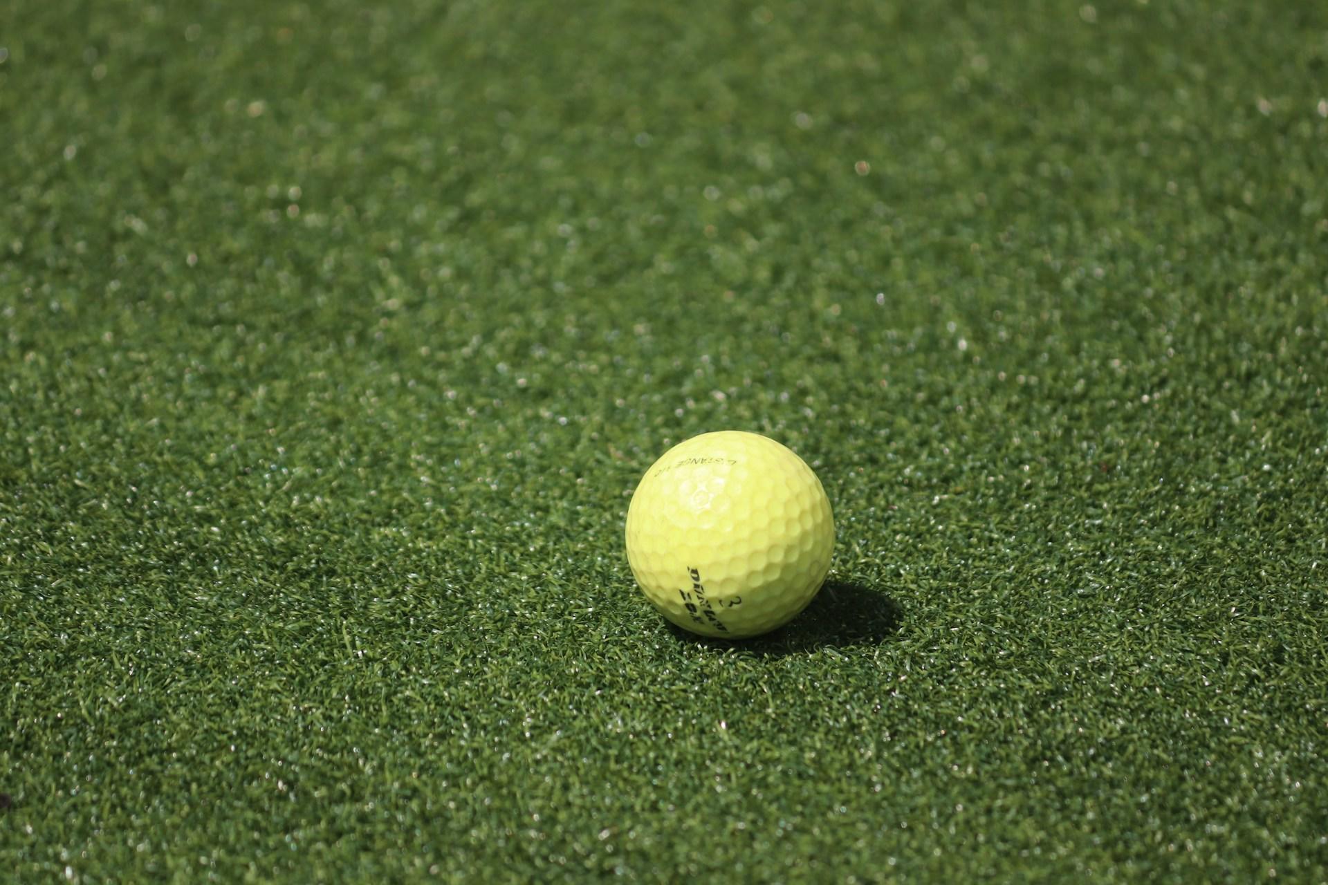 gelber Tennisball liegt auf dem Rasen