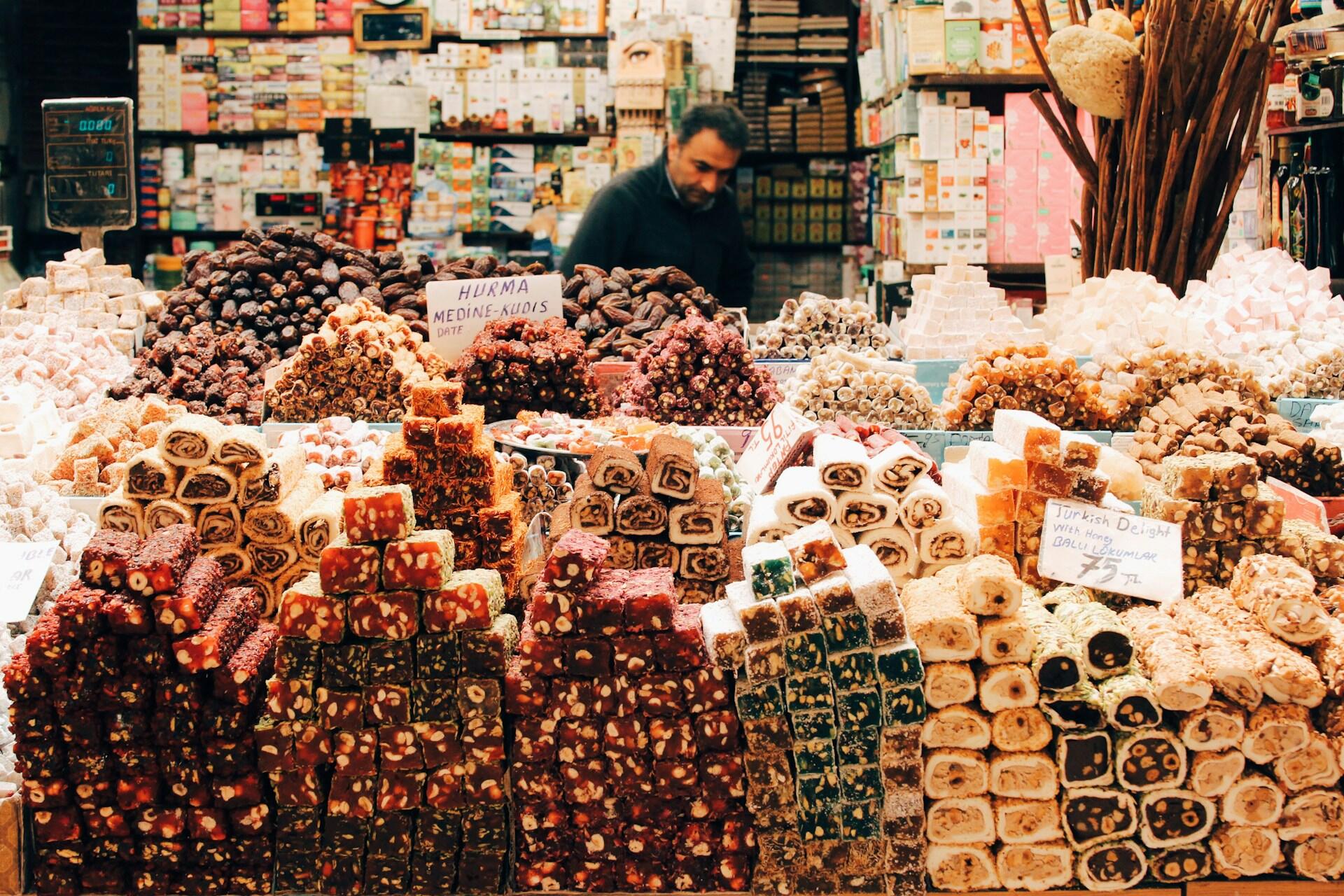 Marktstand mit türkischen Süßigkeiten und Mann dahinter.