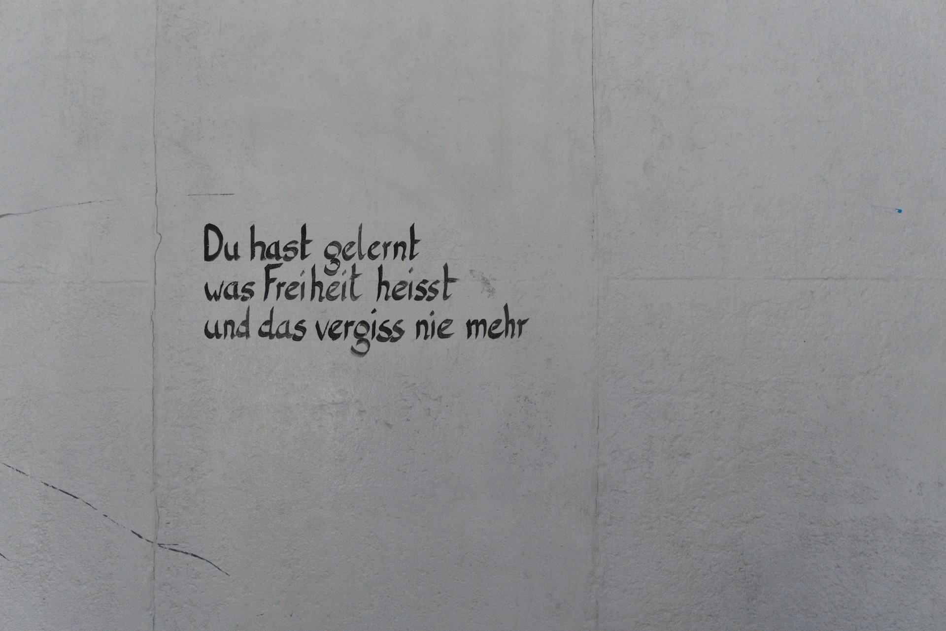 In schwarz steht ein Satz auf eine weiße Wand geschrieben