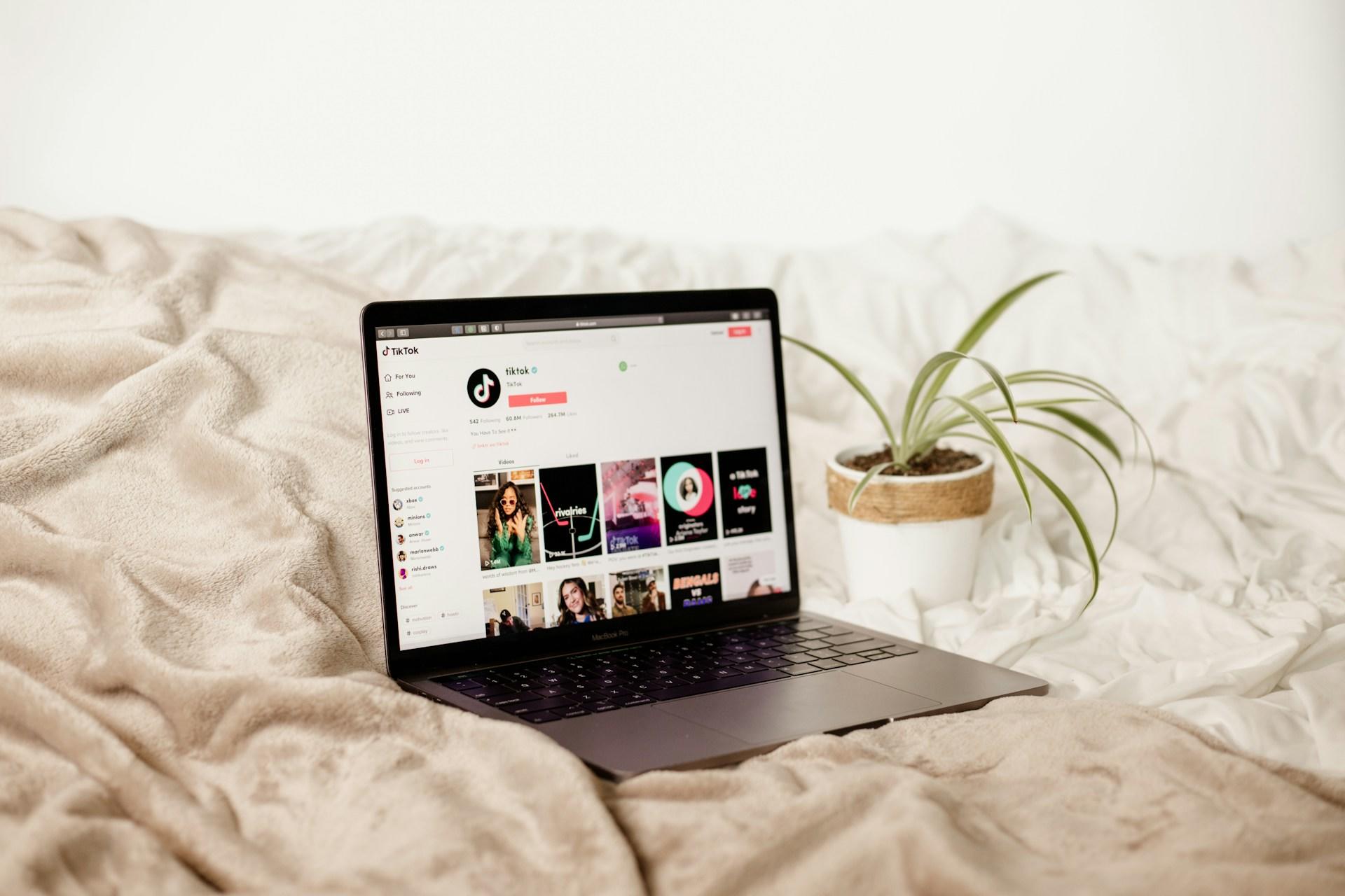 TikTok Webseite auf einem Laptop, der auf einer beigen Decke liegt
