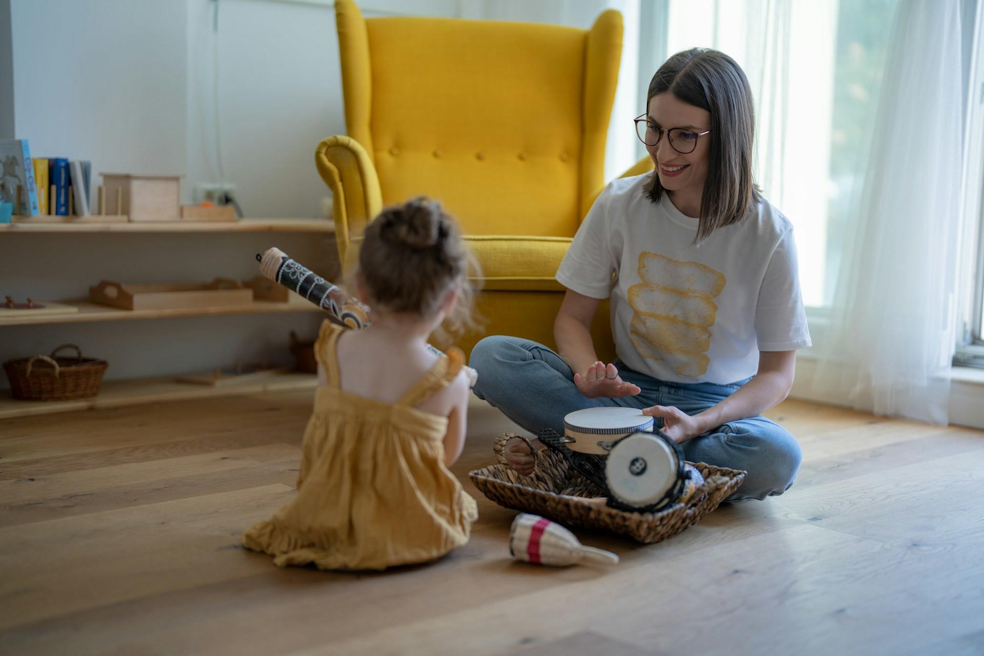 Frau und Mädchen sitzen mit Instrumenten auf dem Boden.