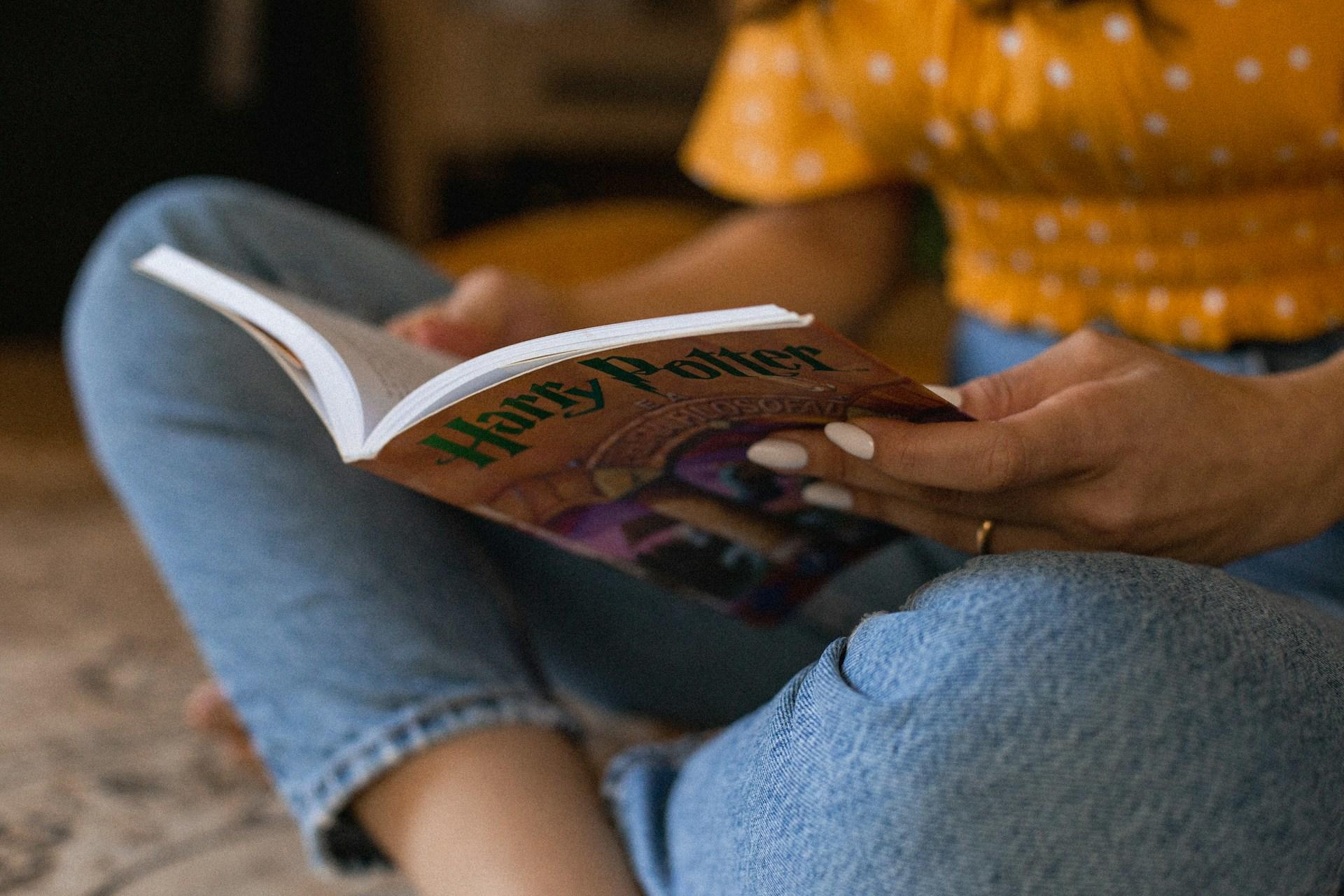 Person im Schneidersitz mit Buch in der Hand.