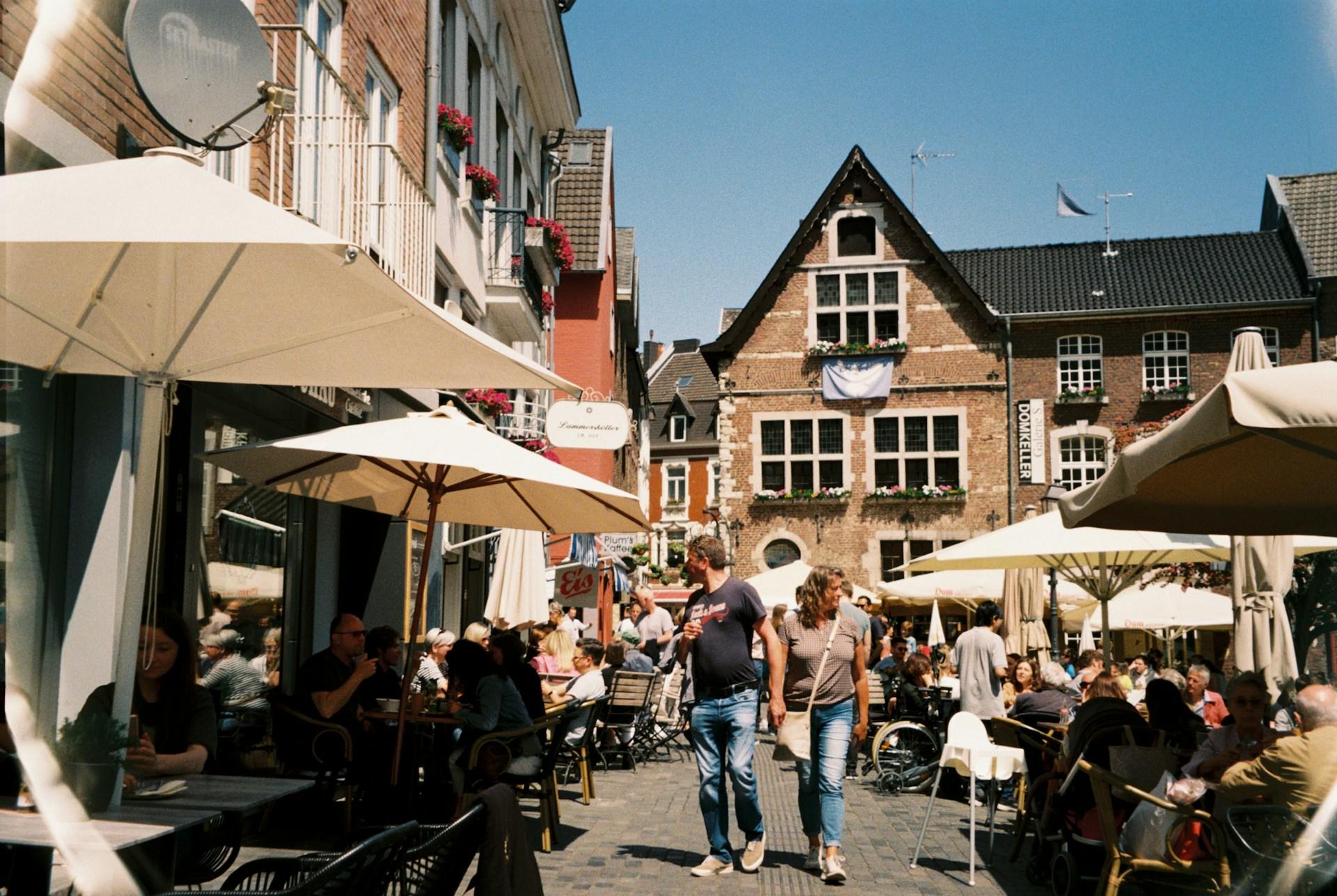 Belebte Straße mit Menschen in Cafés.