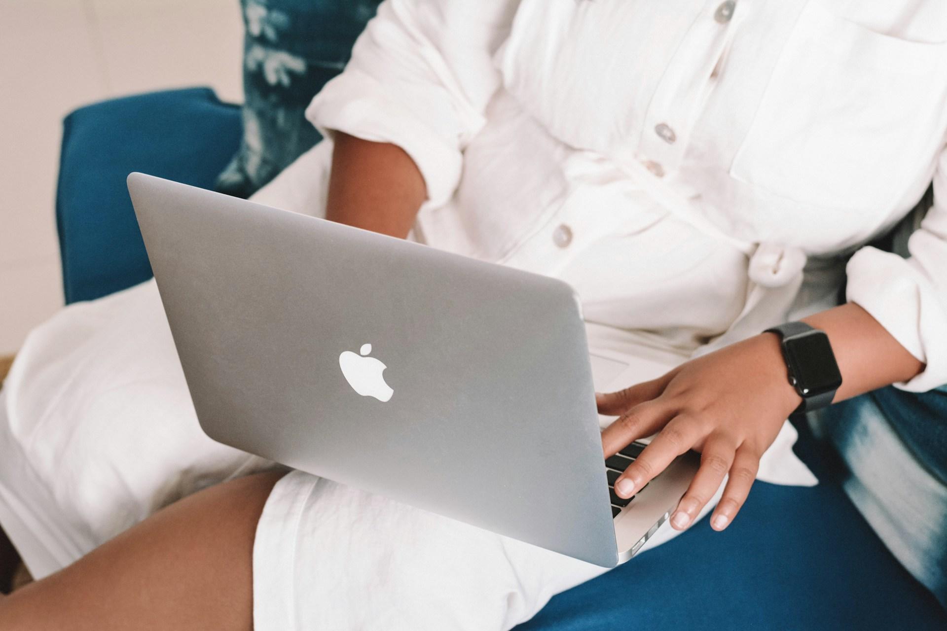 Frau sitzt mit Laptop auf dem Schoß.