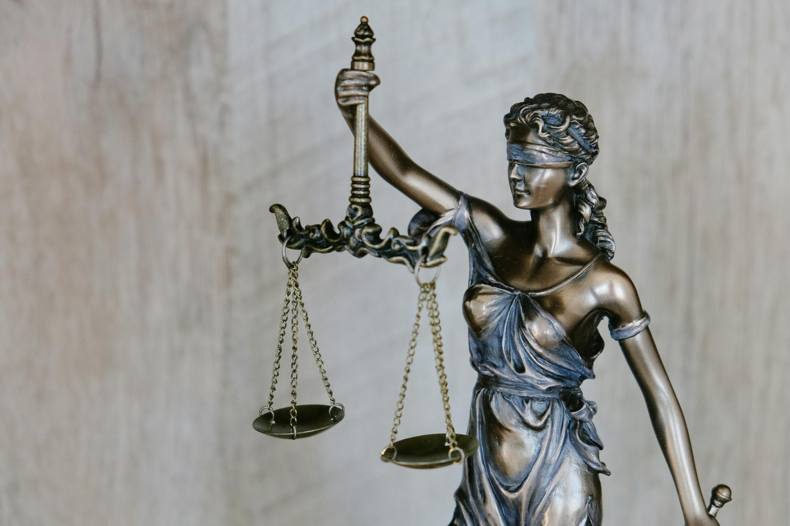 Eine Frauenstatue die eine Waage hält und eine Augenbinde trägt.