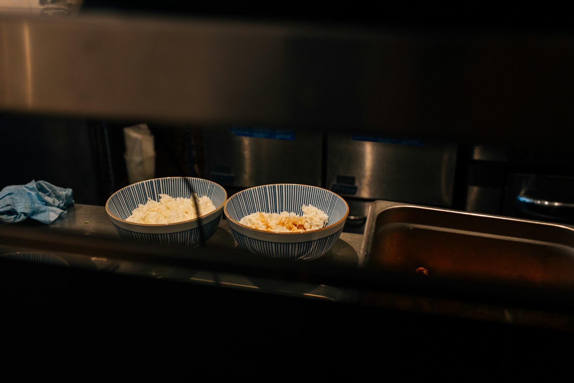 Zwei Schüsseln mit Reis auf einer Ablage.