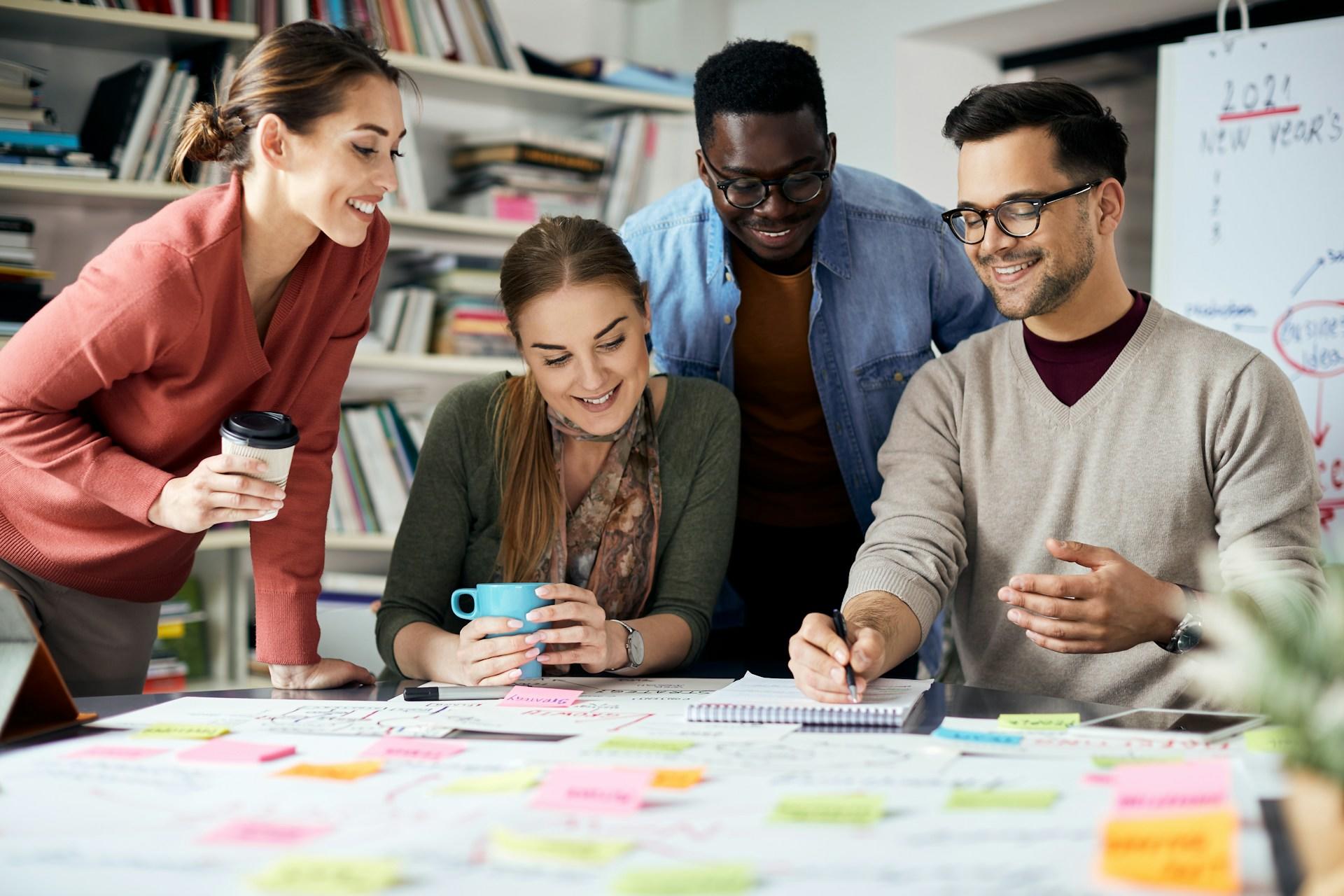 Vier Personen schauen auf einen Tisch voller Post-Its