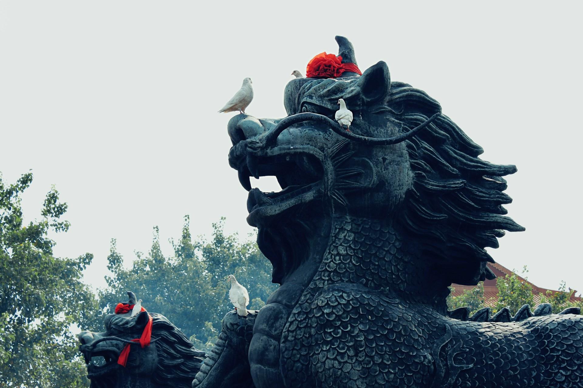 Statue von einem Drachen mit Vögeln drauf.